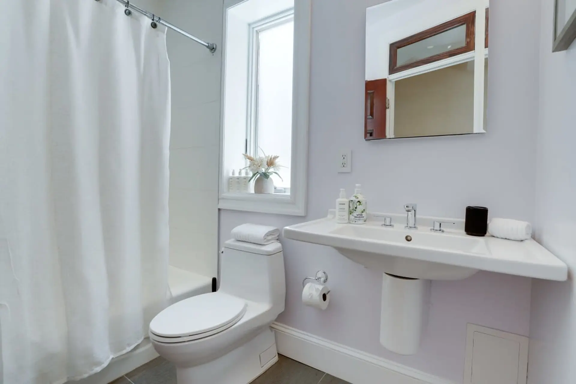 A white toilet and sink with a shower curtain and mirror.