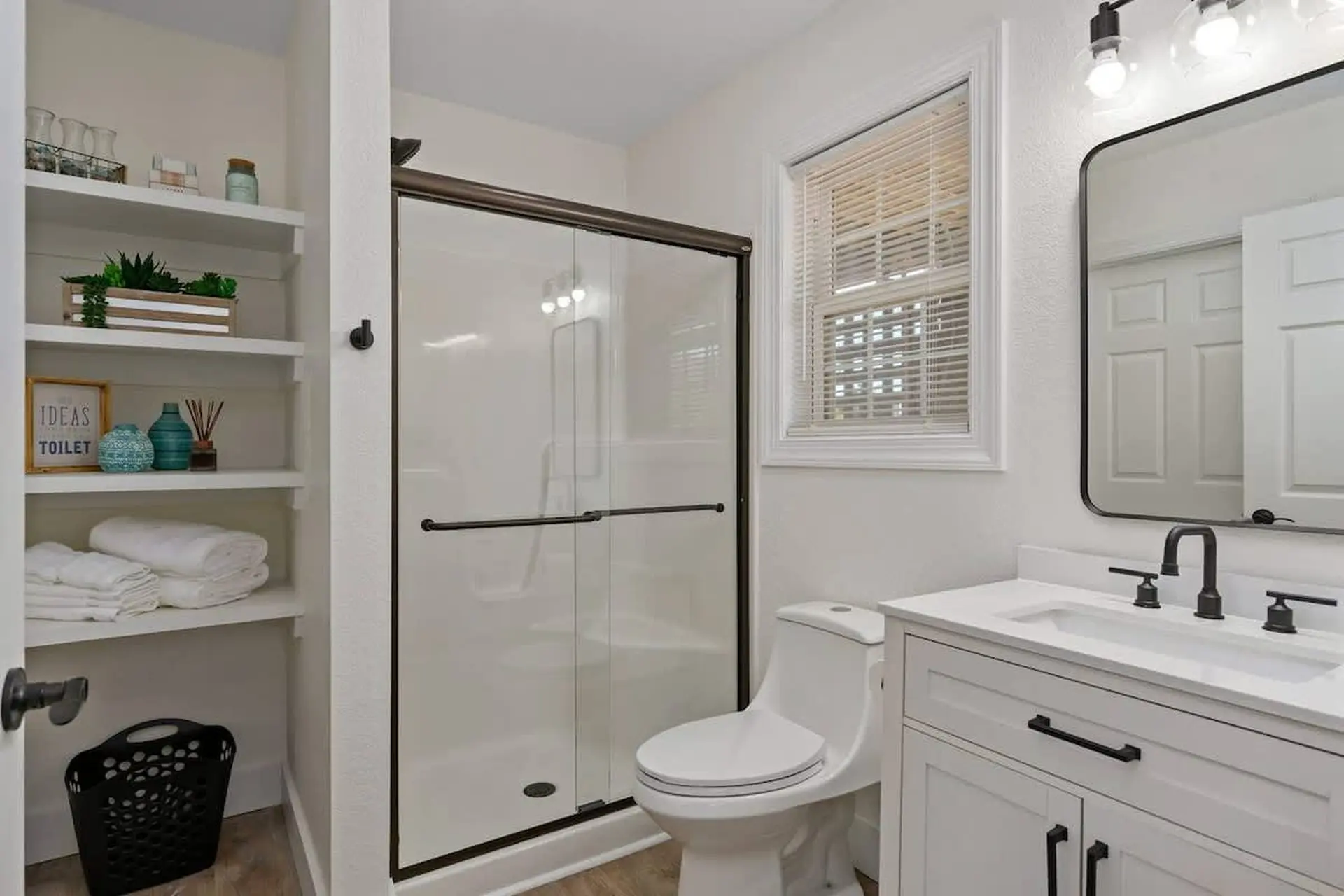 A clean, modern bathroom with a white vanity, black fixtures, and a walk-in shower.