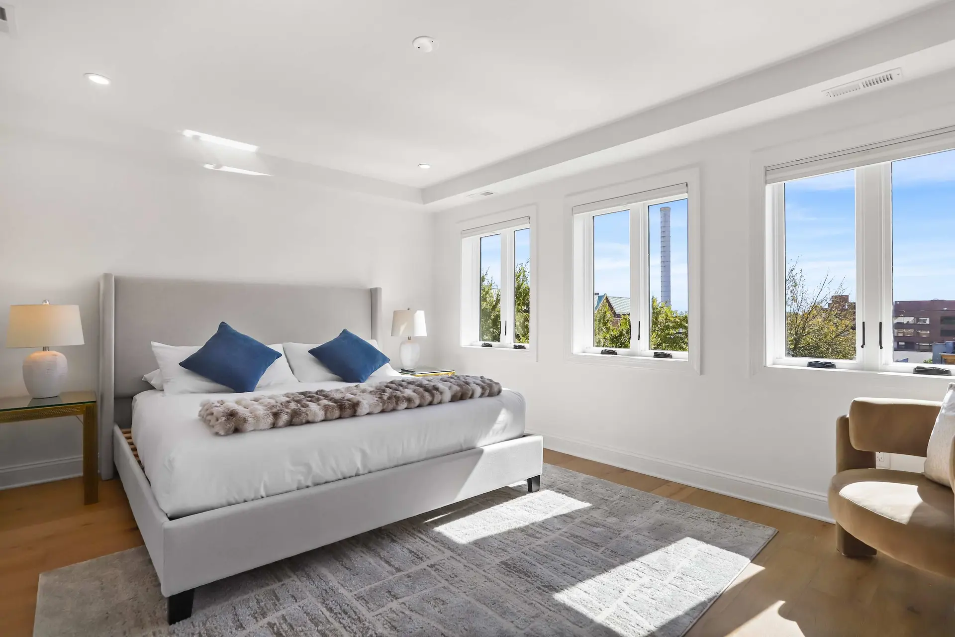 A spacious, modern bedroom with a king-size bed, elegant lamps, and a large window with a scenic vie