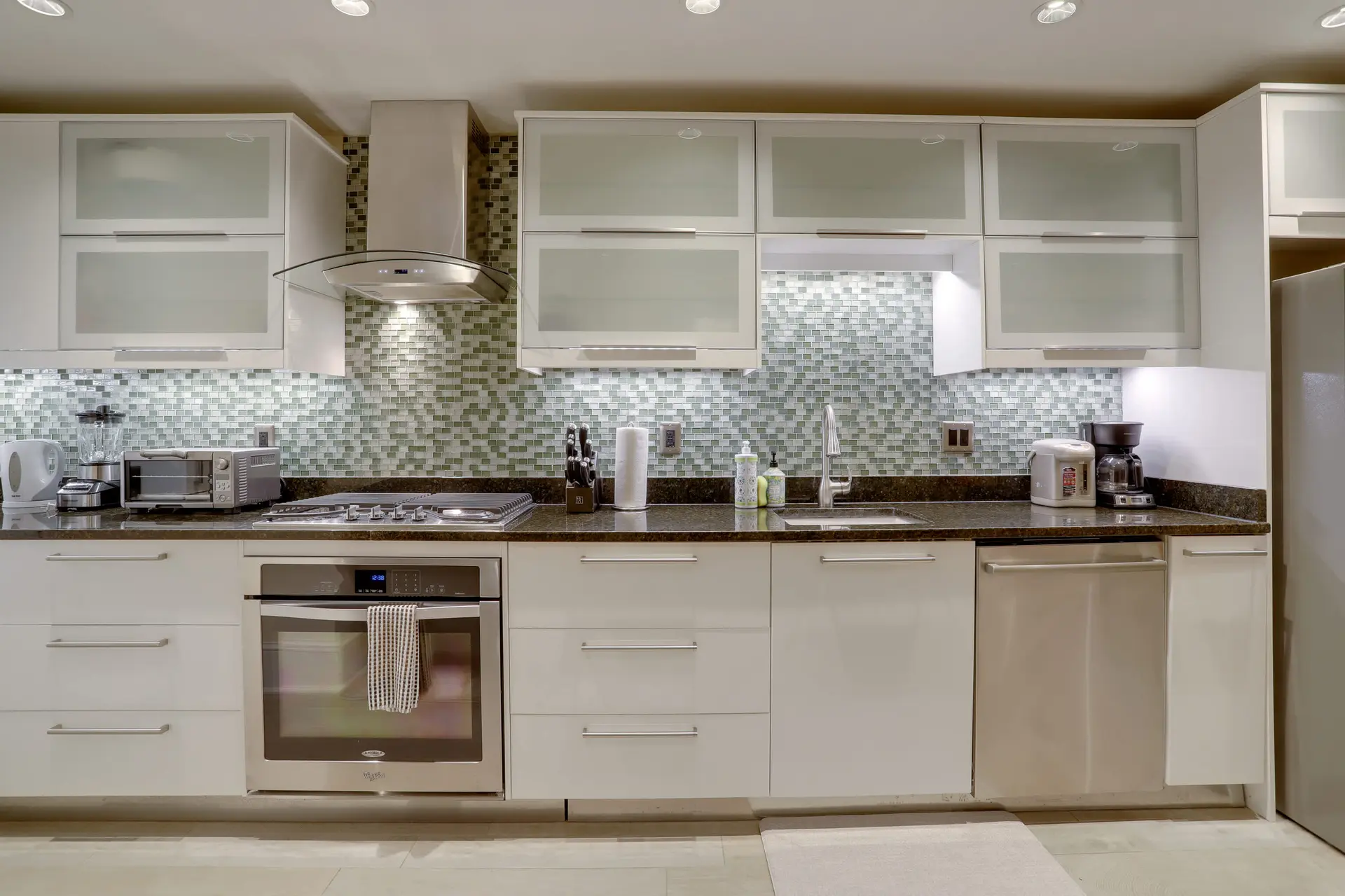 A modern kitchen with white cabinets and a stainless steel appliance.