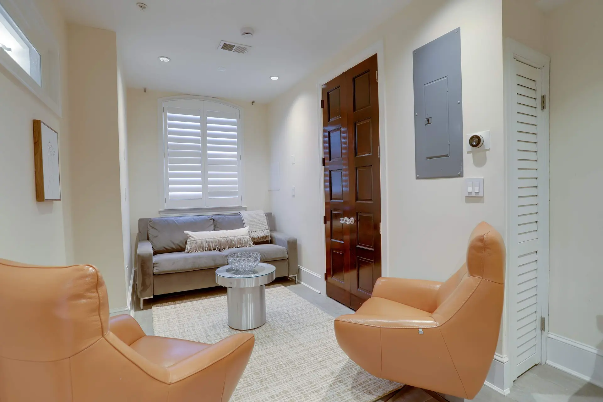 A sitting area with two armchairs, a sofa, a round coffee table, and a wooden door.