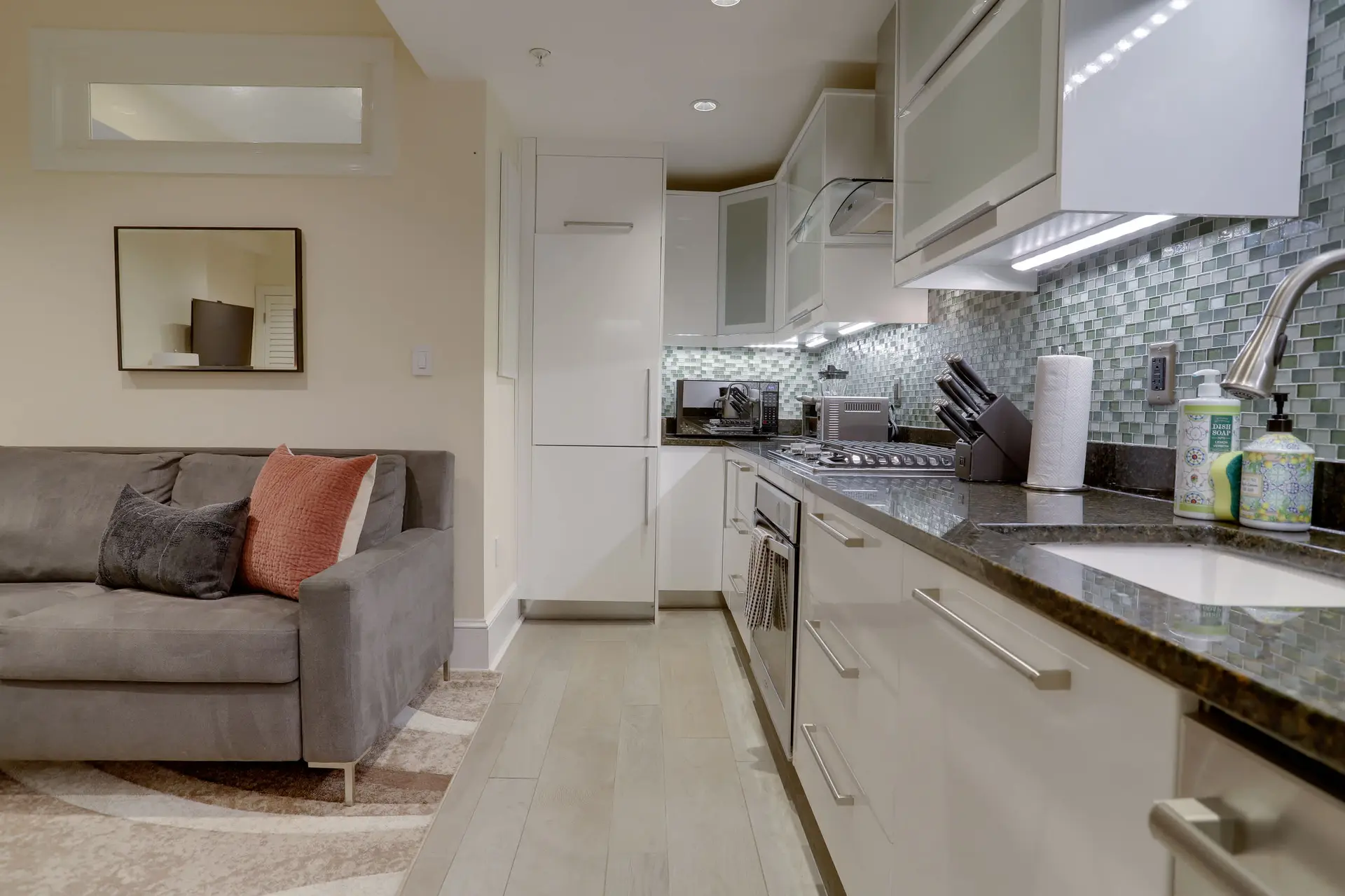 Modern kitchen with a grey couch and white cabinets.