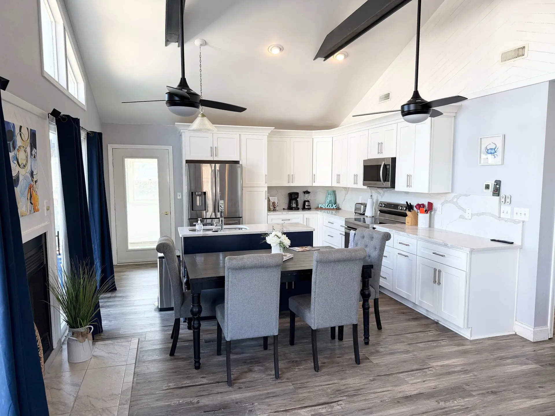 Kitchen with vaulted ceiling, ceiling fans, and dining set in front of island.