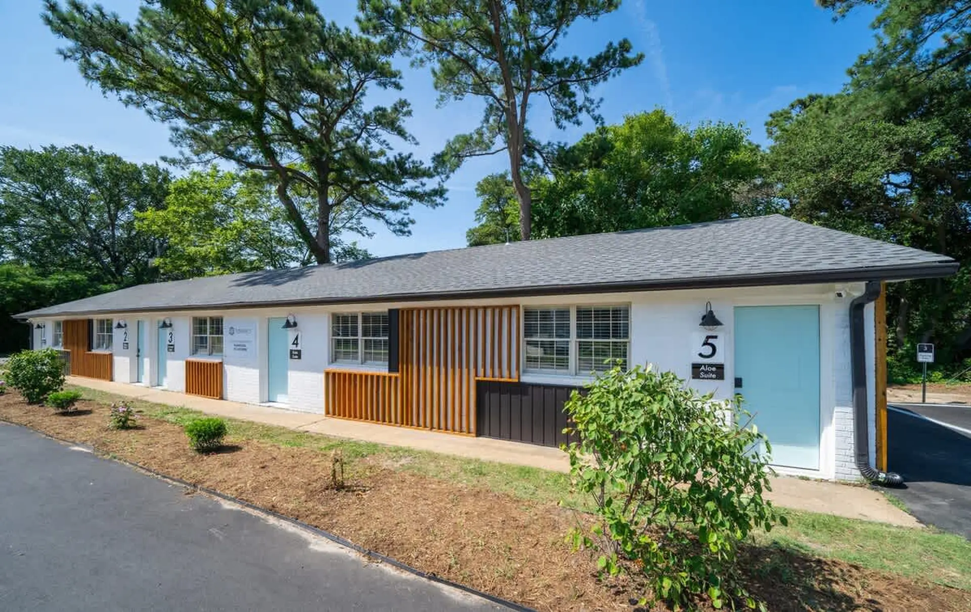 A row of white suites with blue doors and numbered signs.
