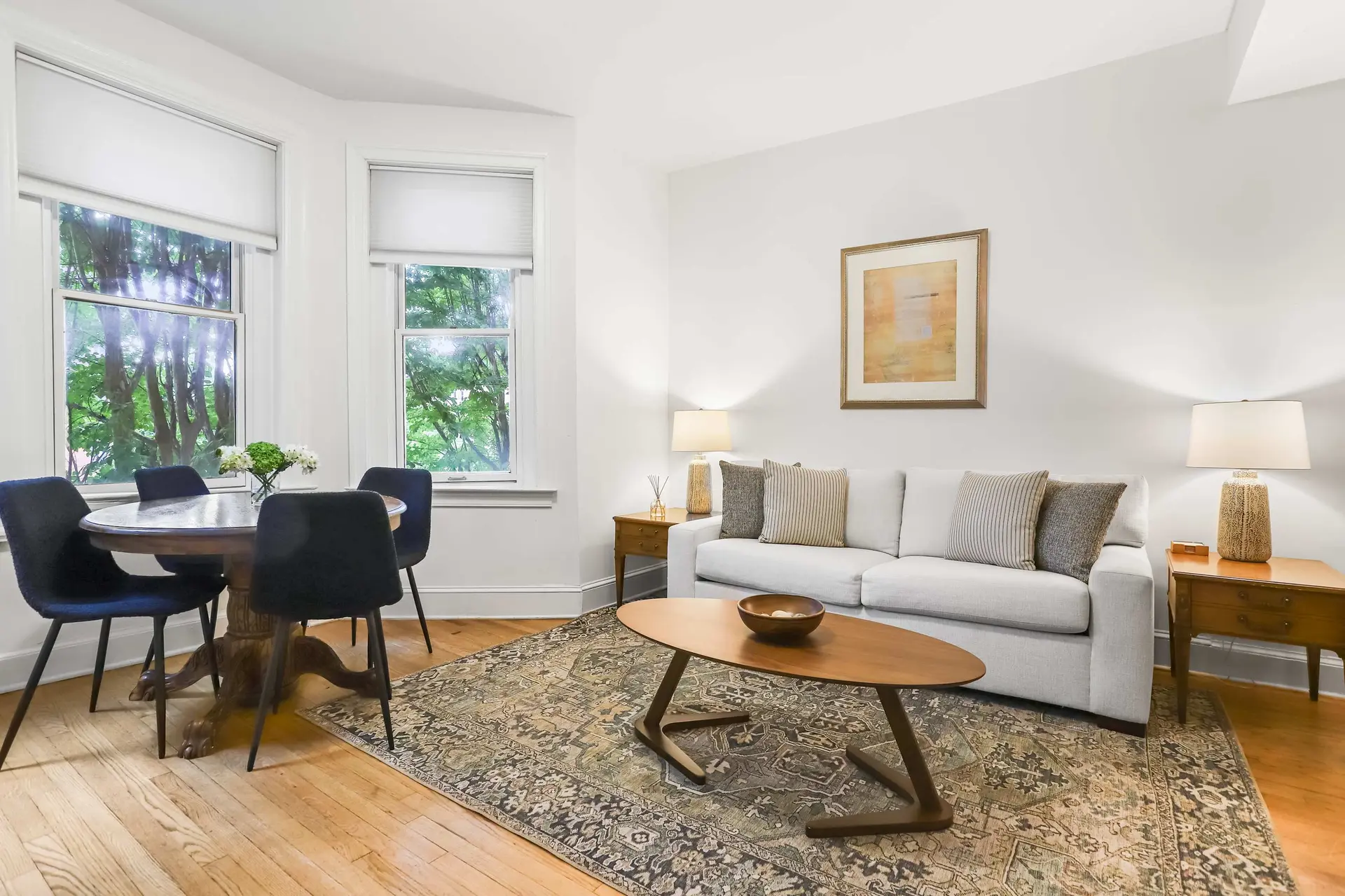 A living room and dining area with a sofa, coffee table, rug, and dining set.