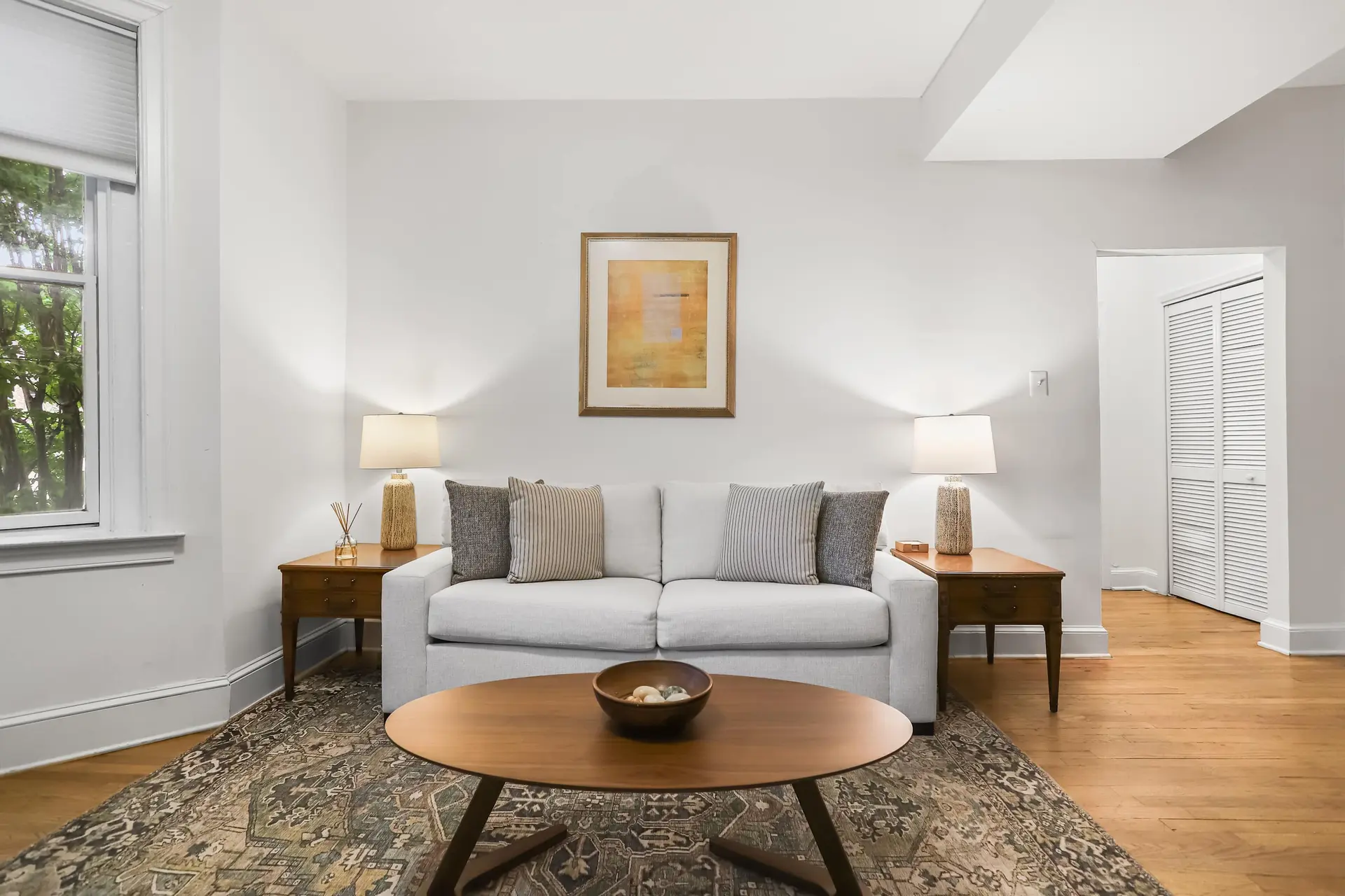 A modern living room with a white sofa, wooden coffee table, and large patterned rug.