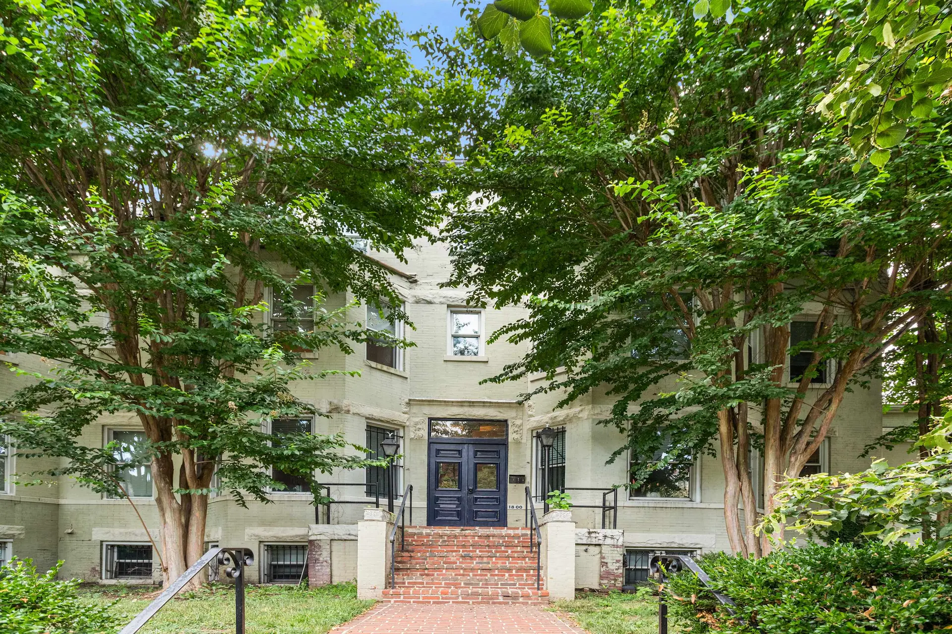 A light green apartment building with a large double door.