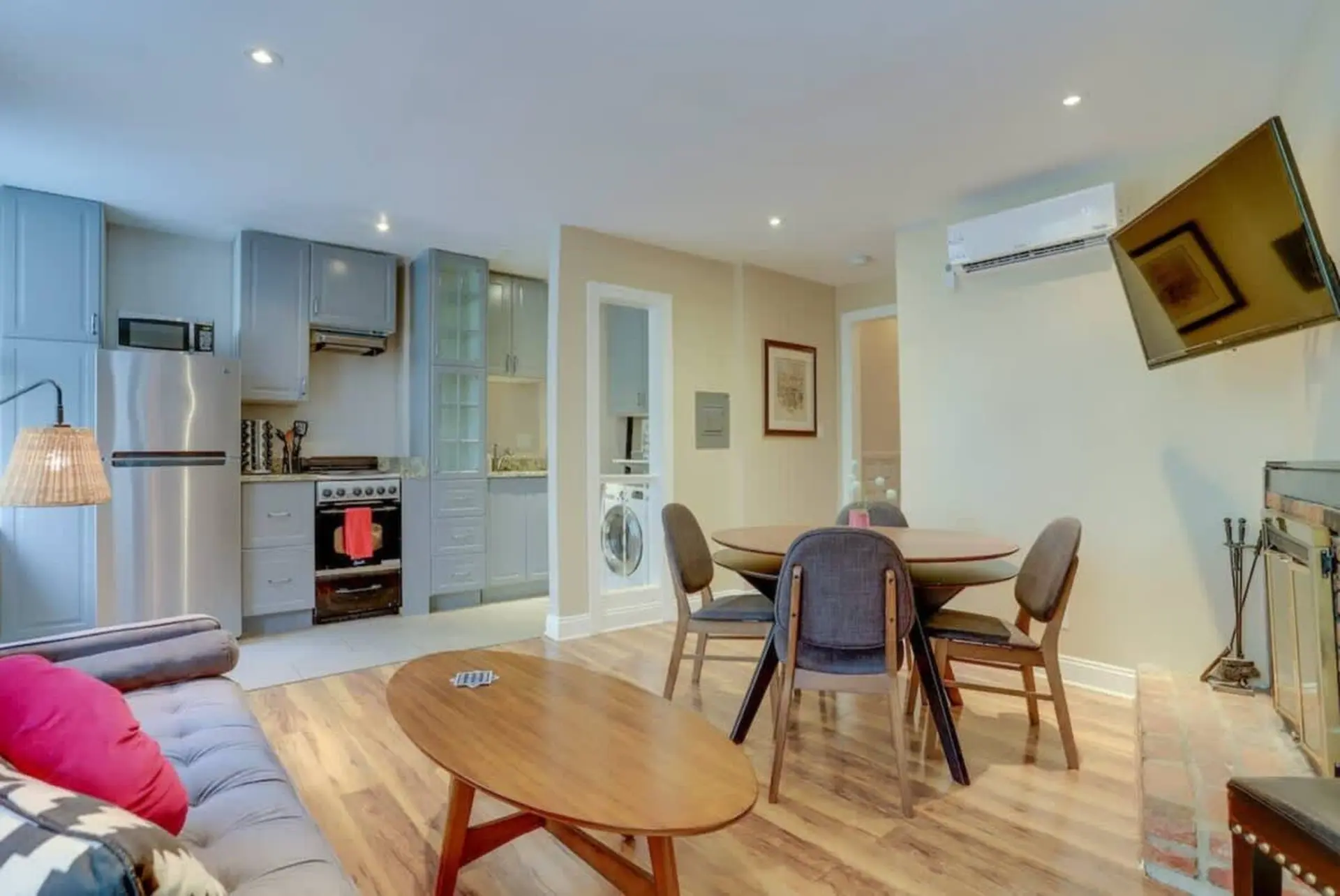 A living room and kitchen area with a sofa, table, chairs, and TV.