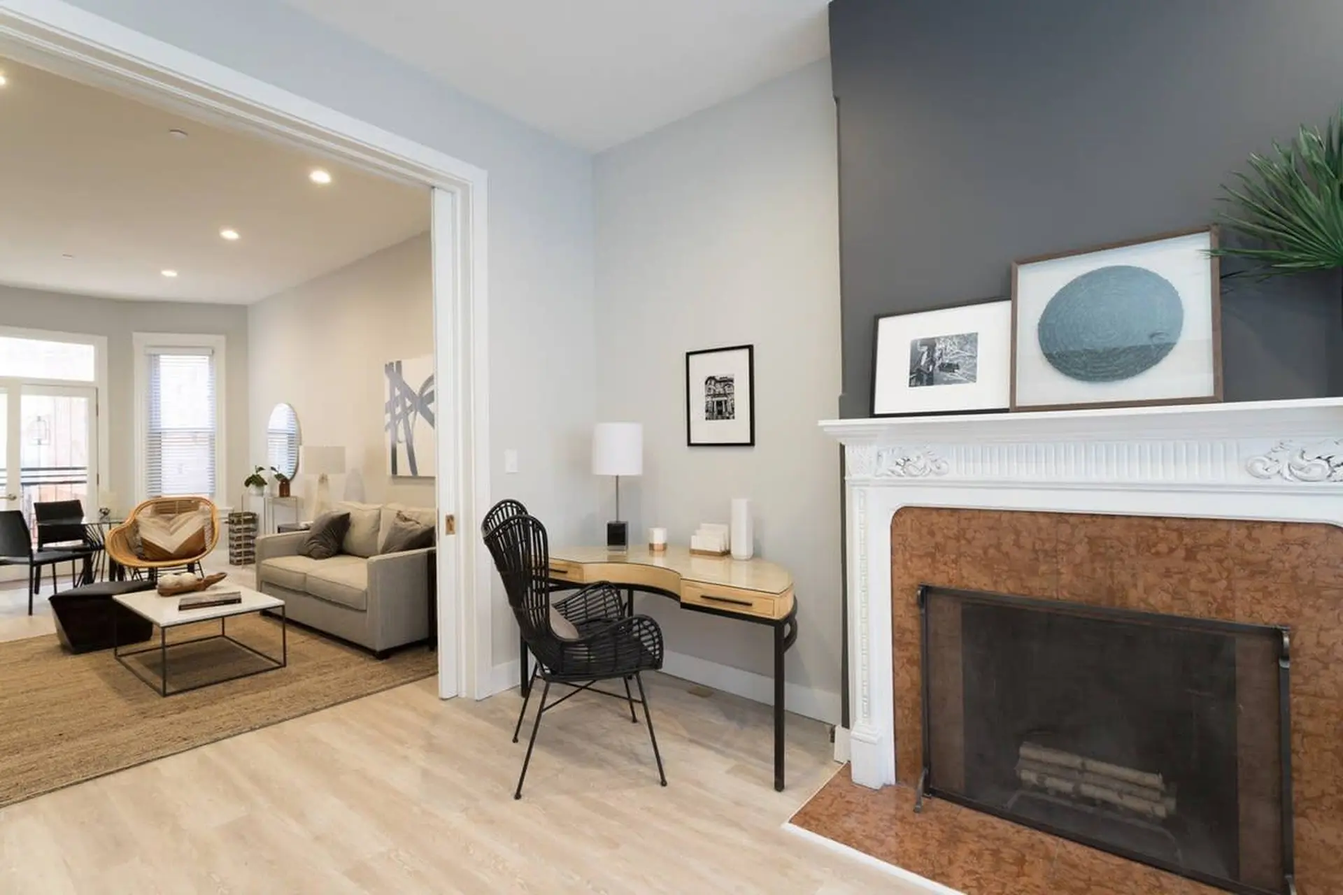 A living room with a fireplace, desk, sofa, and chairs.