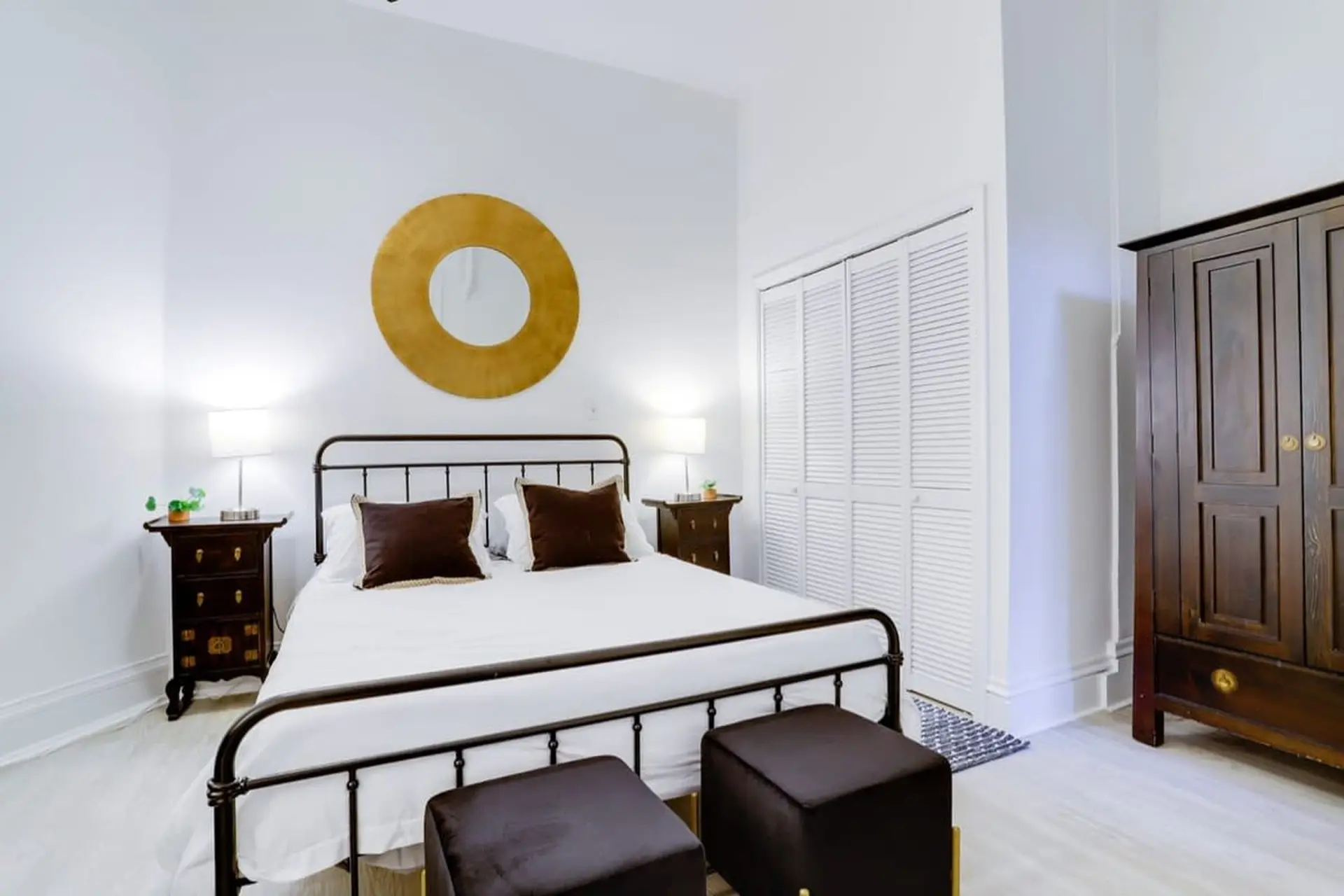 A bedroom with a bed, nightstands, a large mirror, and a wardrobe.