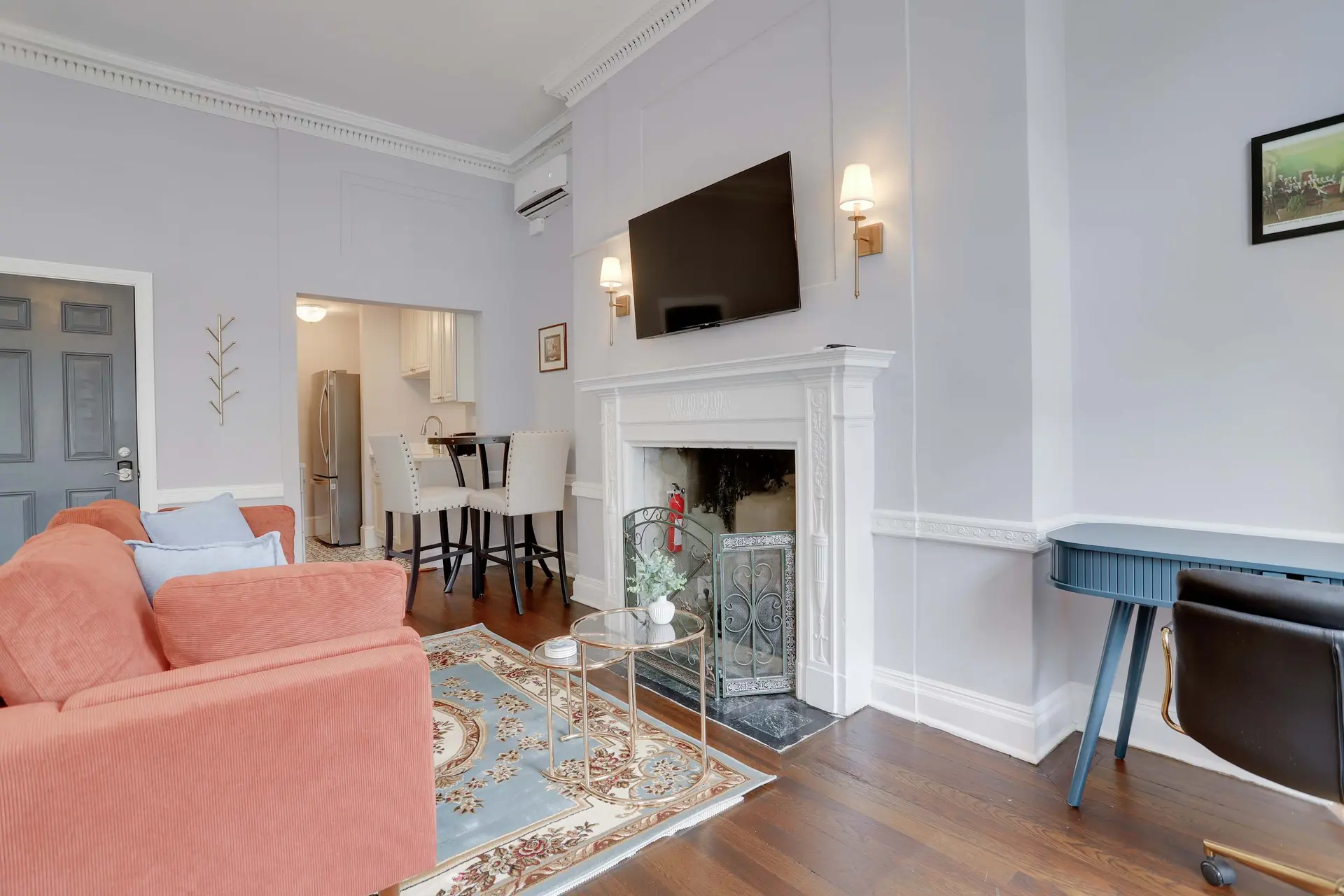 A living room with a coral sofa, a fireplace, and a desk.