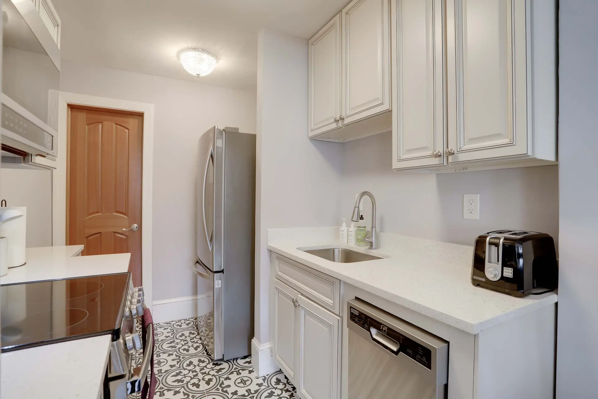 A kitchen with white cabinets, a stainless steel refrigerator, and a wooden door.
