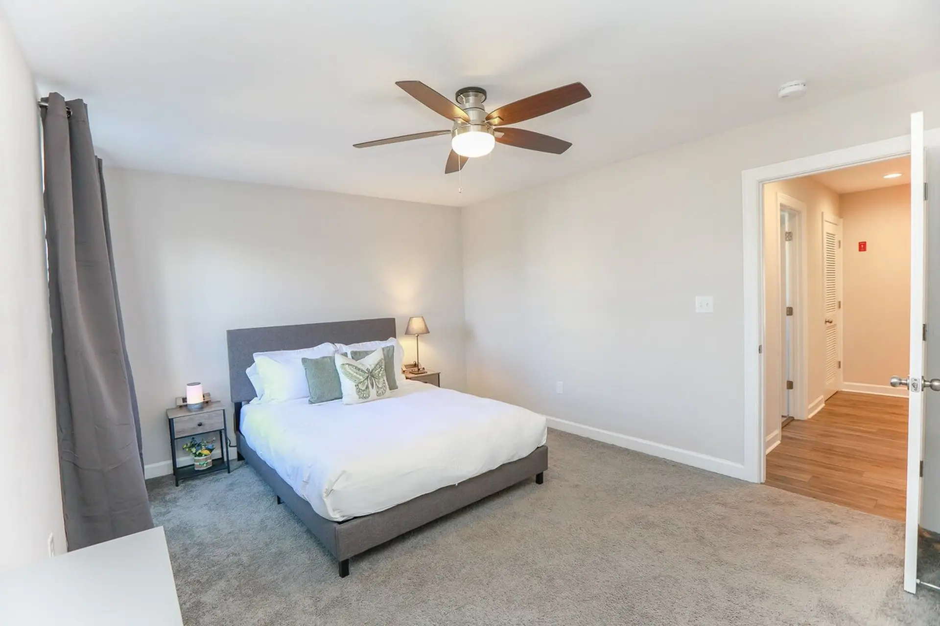 Bedroom with a bed, ceiling fan, and doorway to a hallway.