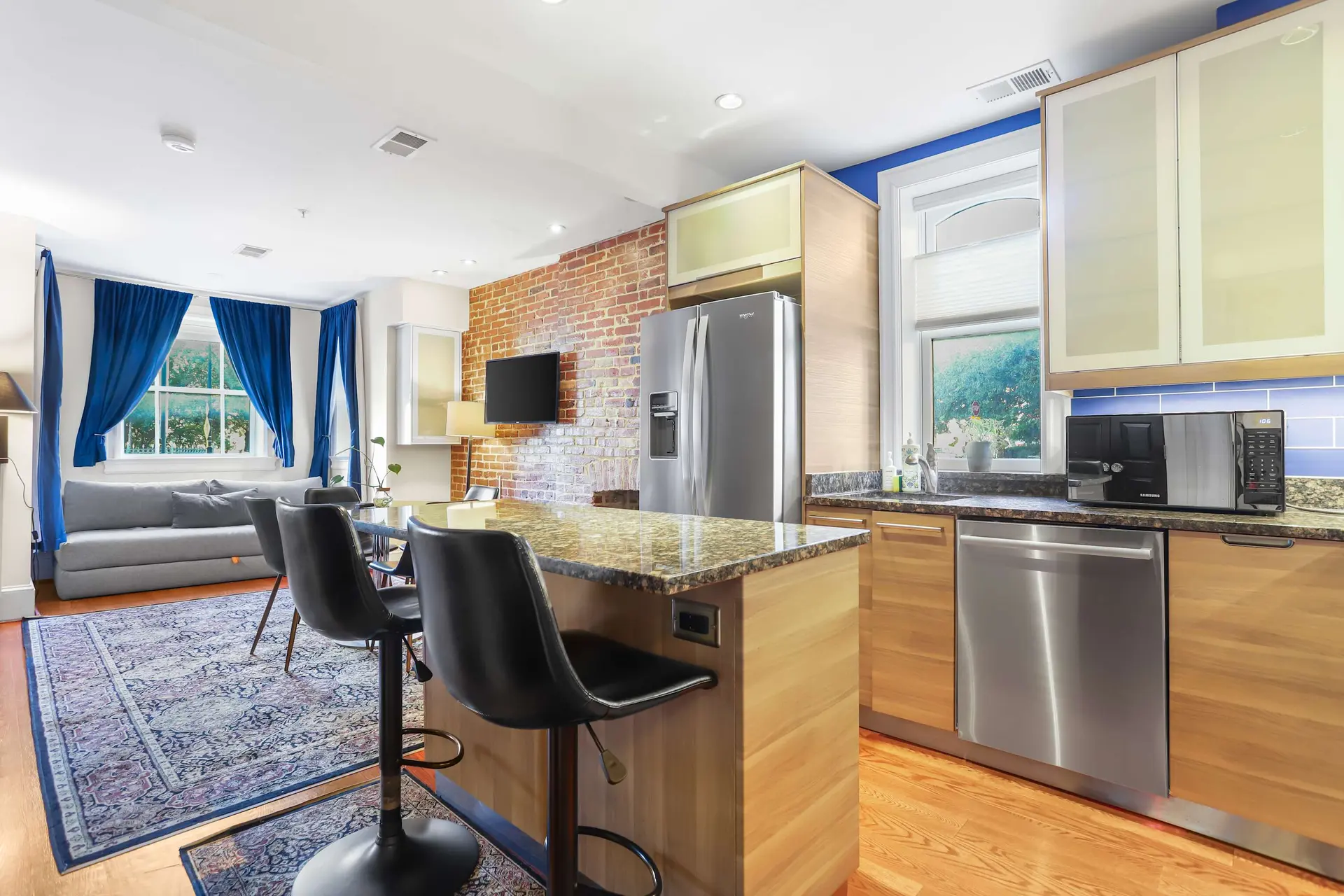 Modern kitchen with a brick accent wall, stainless steel appliances, and a granite-topped island wit