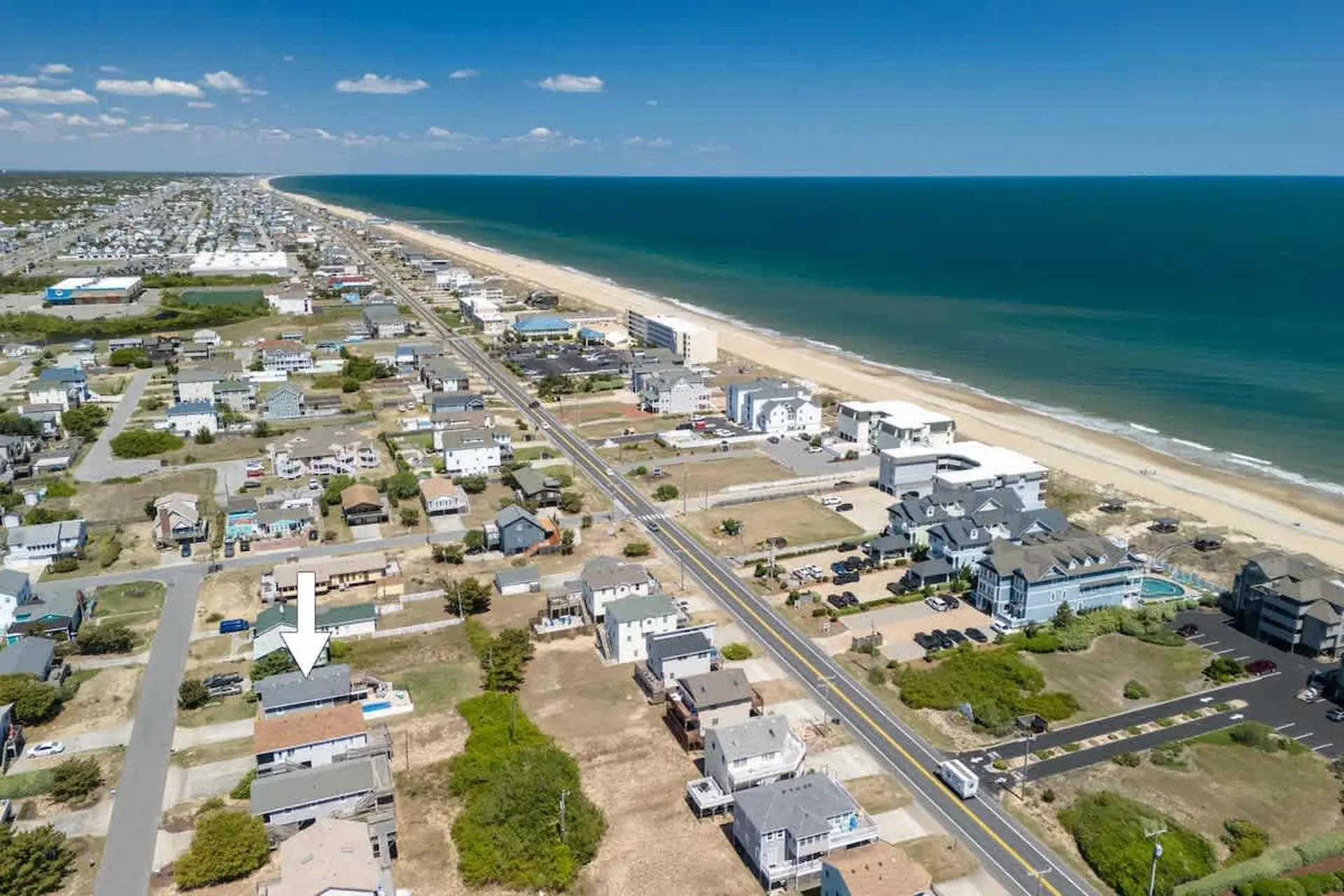 Aerial view of beachfront homes and buildings along a highway next to the ocean.