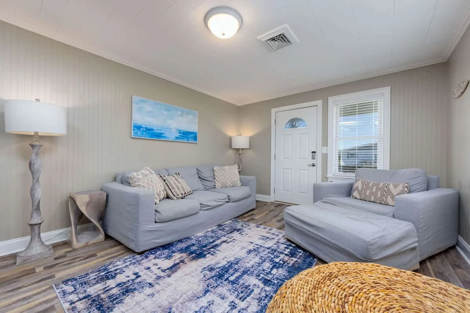 A living room with a grey sofa, ottoman, and rug.