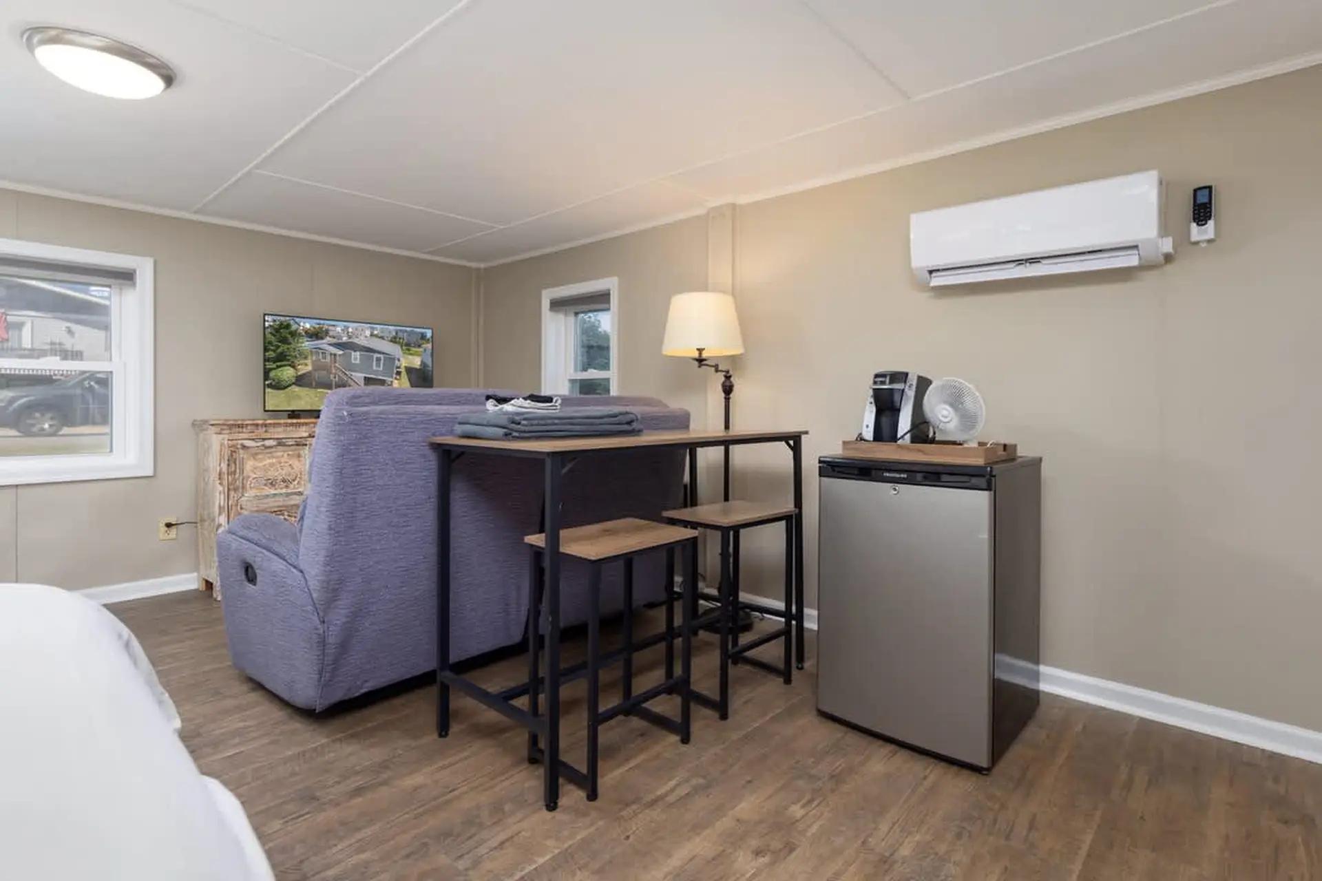A living space with a TV, sofa, dining table, and mini-fridge.