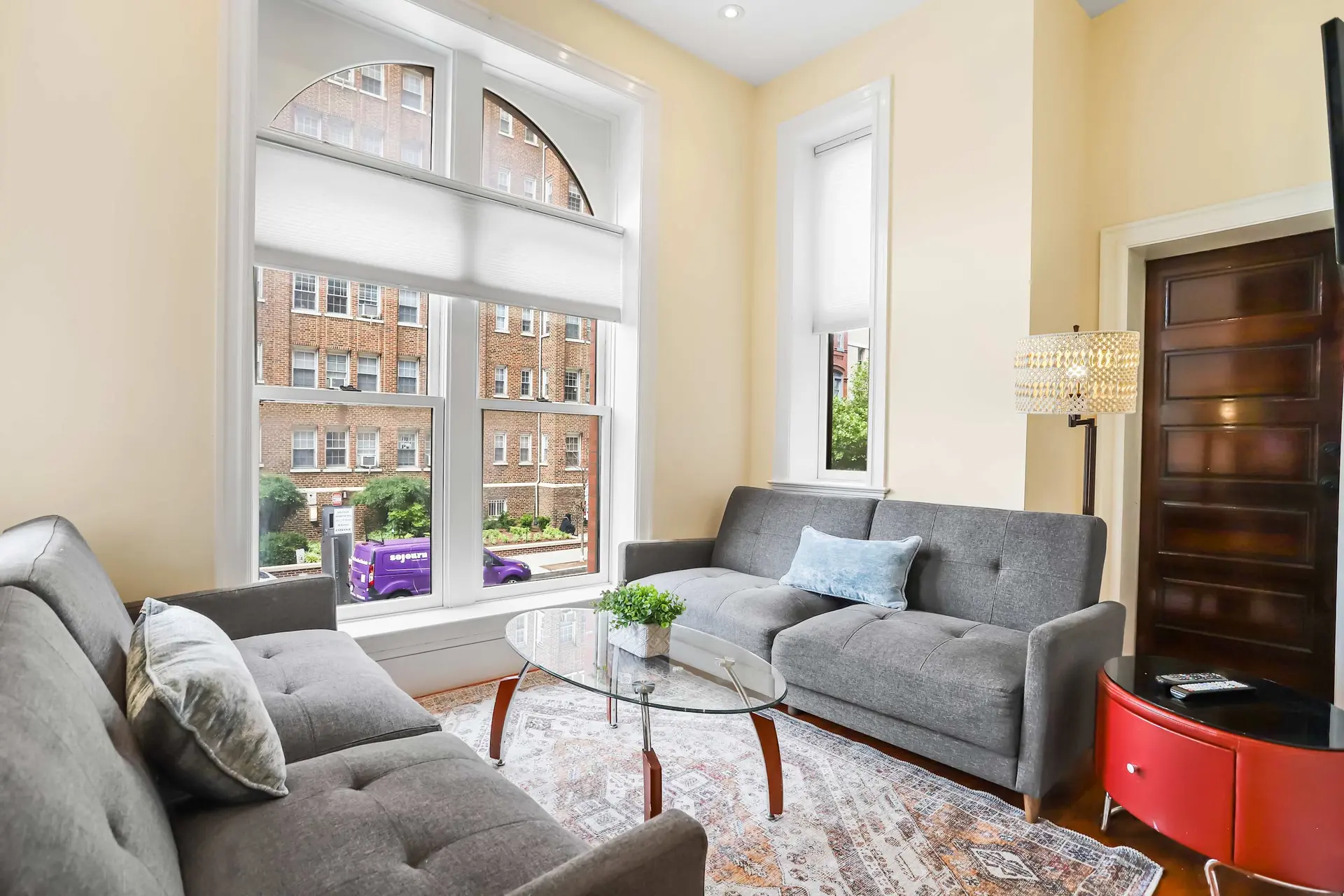 Living room with two grey sofas, a glass coffee table, and a ornate lamp.