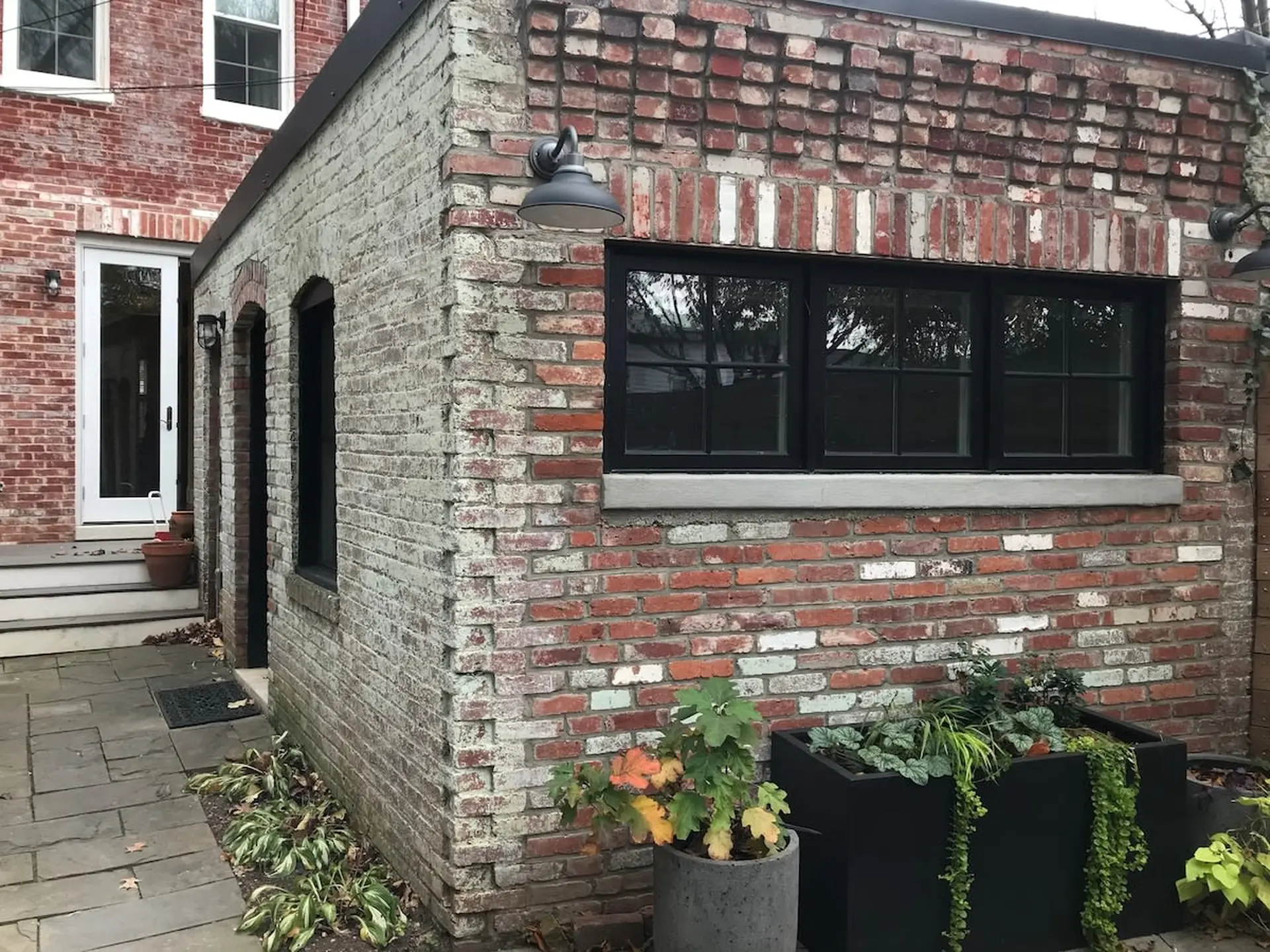 A corner of a brick building with black framed windows and planters.