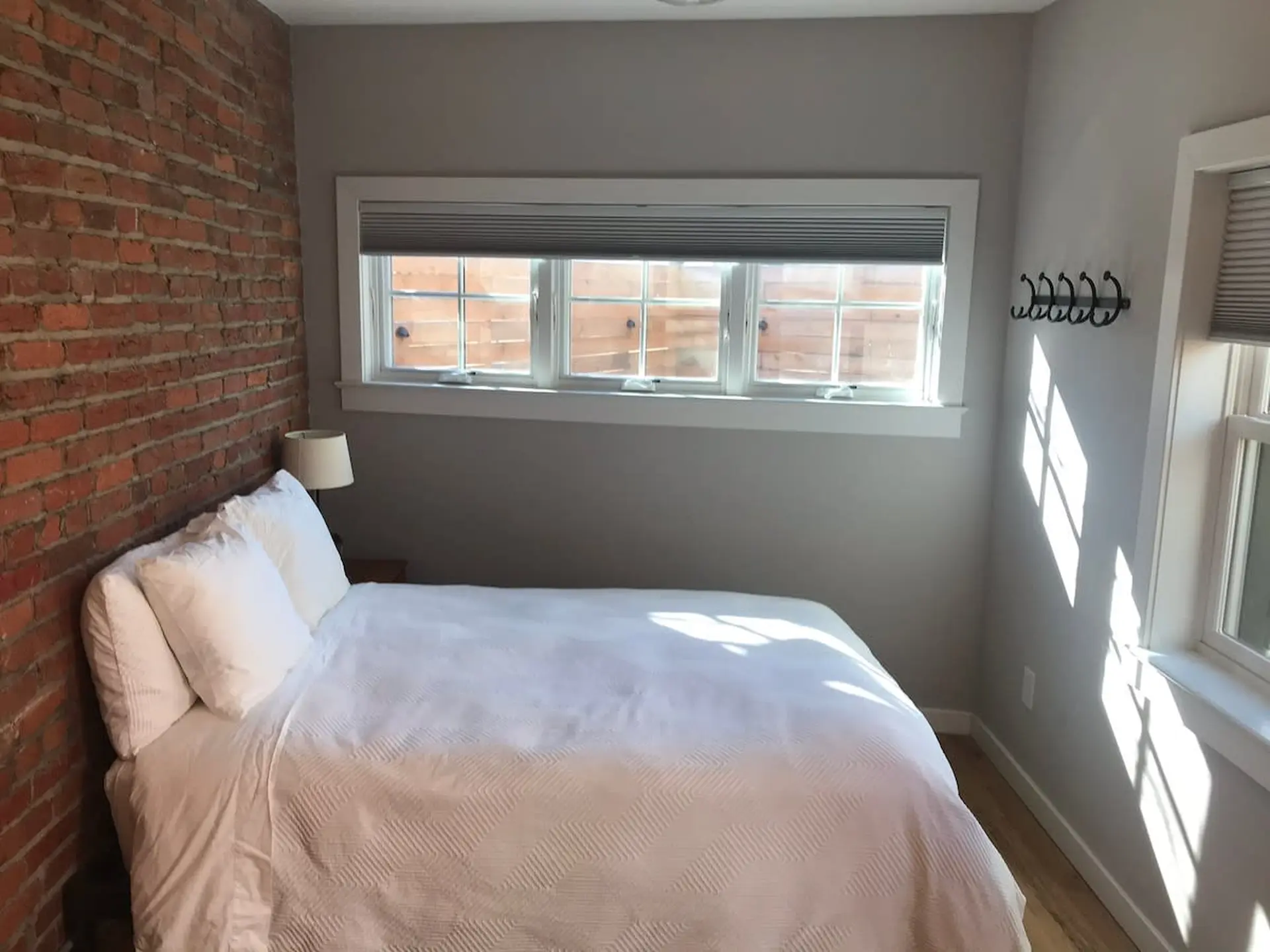 A bedroom with a brick accent wall and a bed with white linens.
