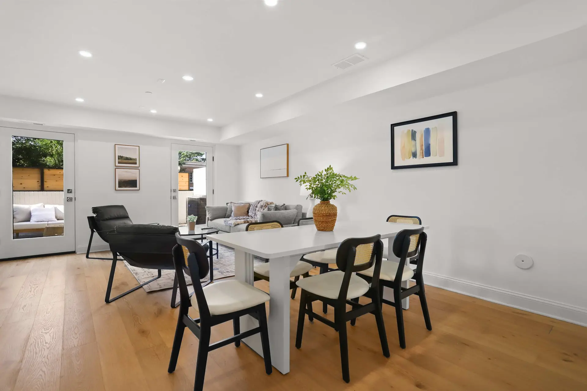 A dining table and chairs sit in front of a couch and door.
