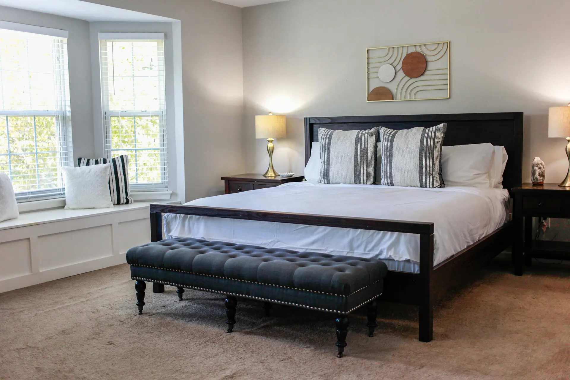 A cozy bedroom with a tufted bench and a dark wood bed.