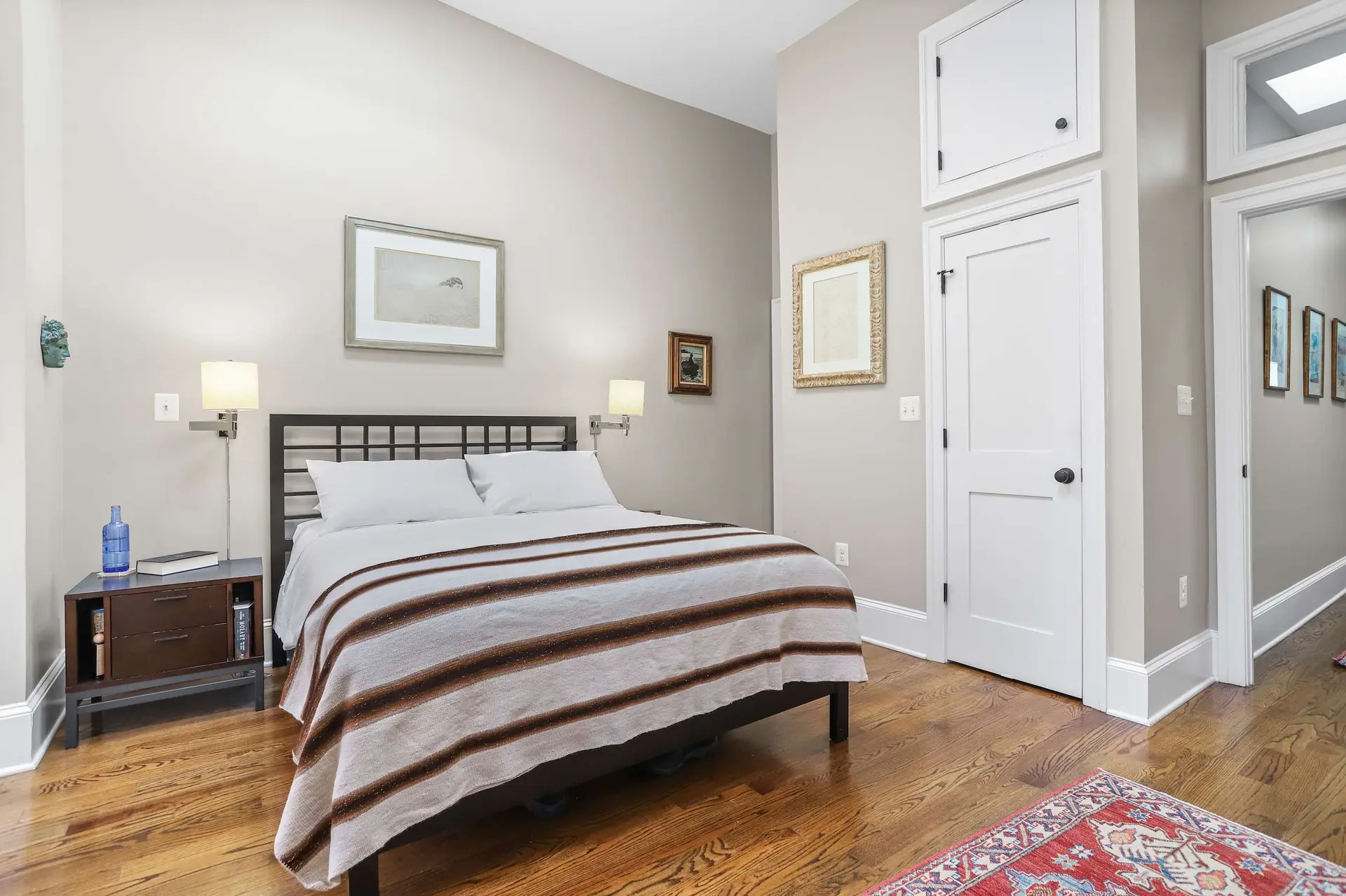 A bedroom with a bed, a nightstand, and two doors.