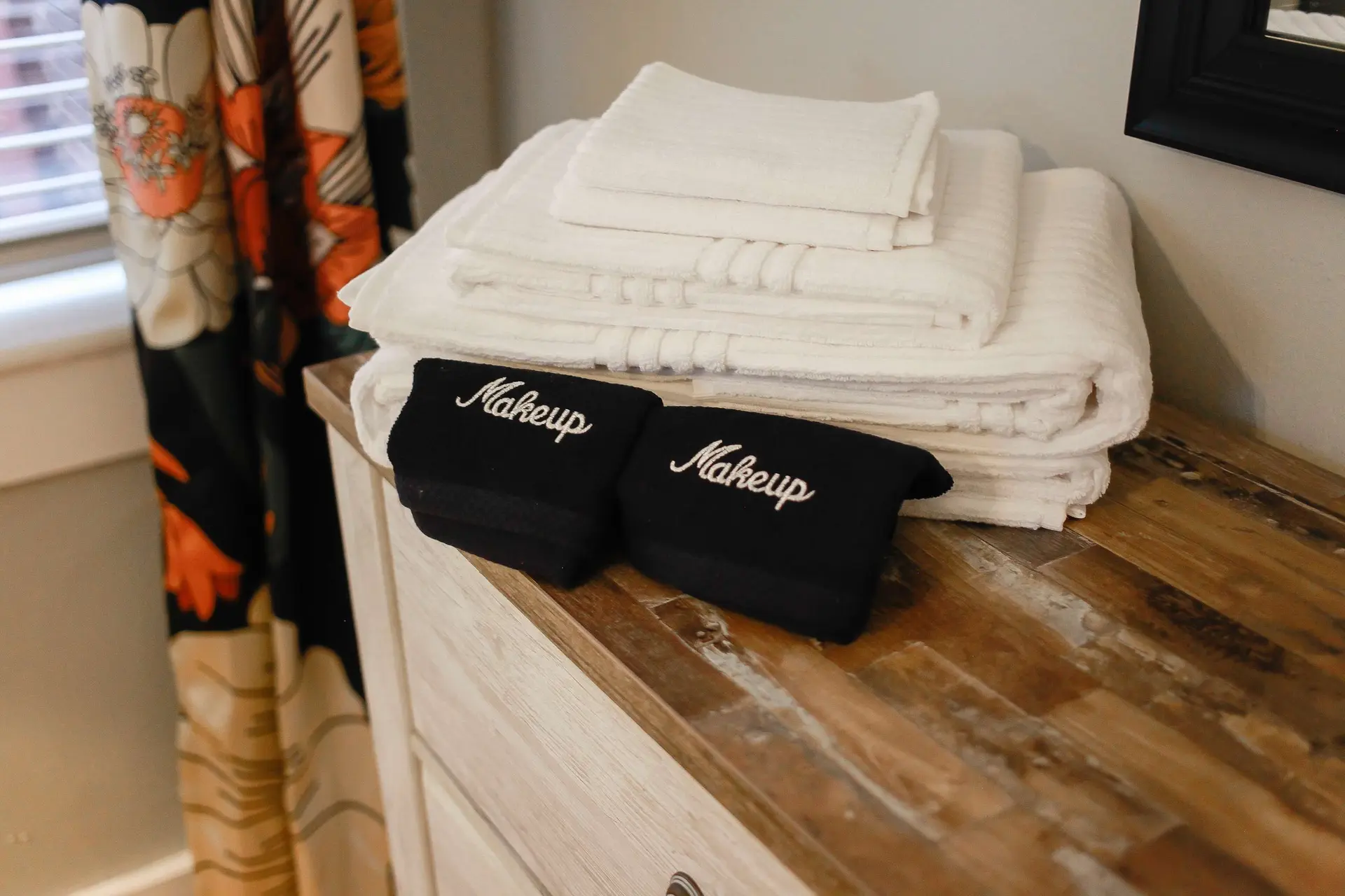 Two black wristbands with the word "Makeup" embroidered in white are placed on top of a stack of whi