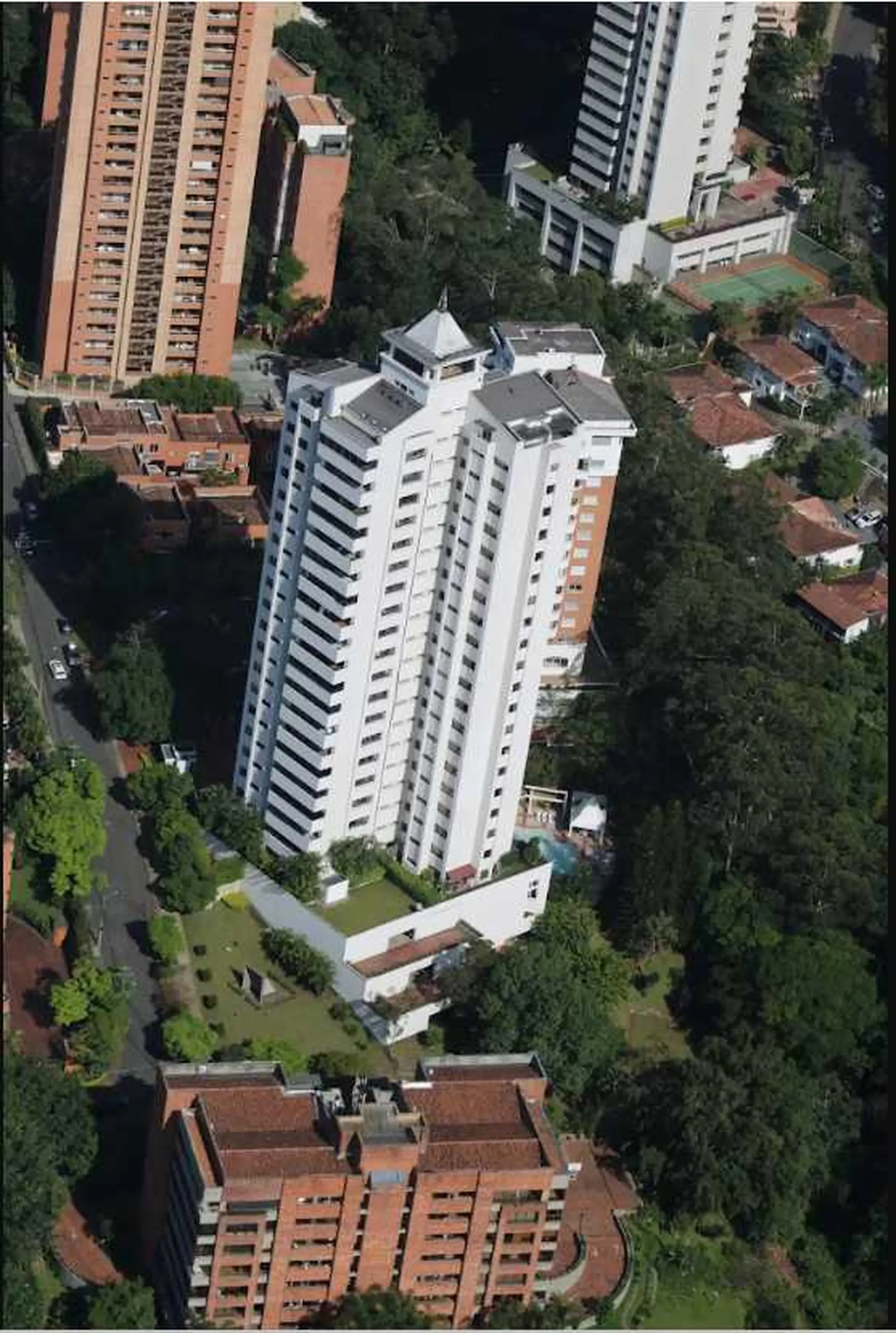 An aerial view of apartment buildings, a tennis court, and trees.