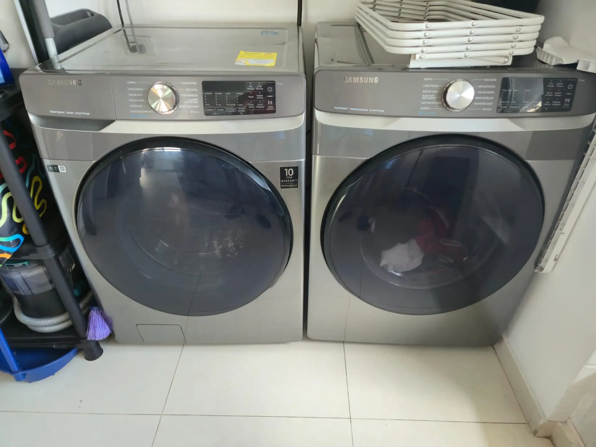 Two Samsung front-load washing machines are side-by-side on a tiled floor.