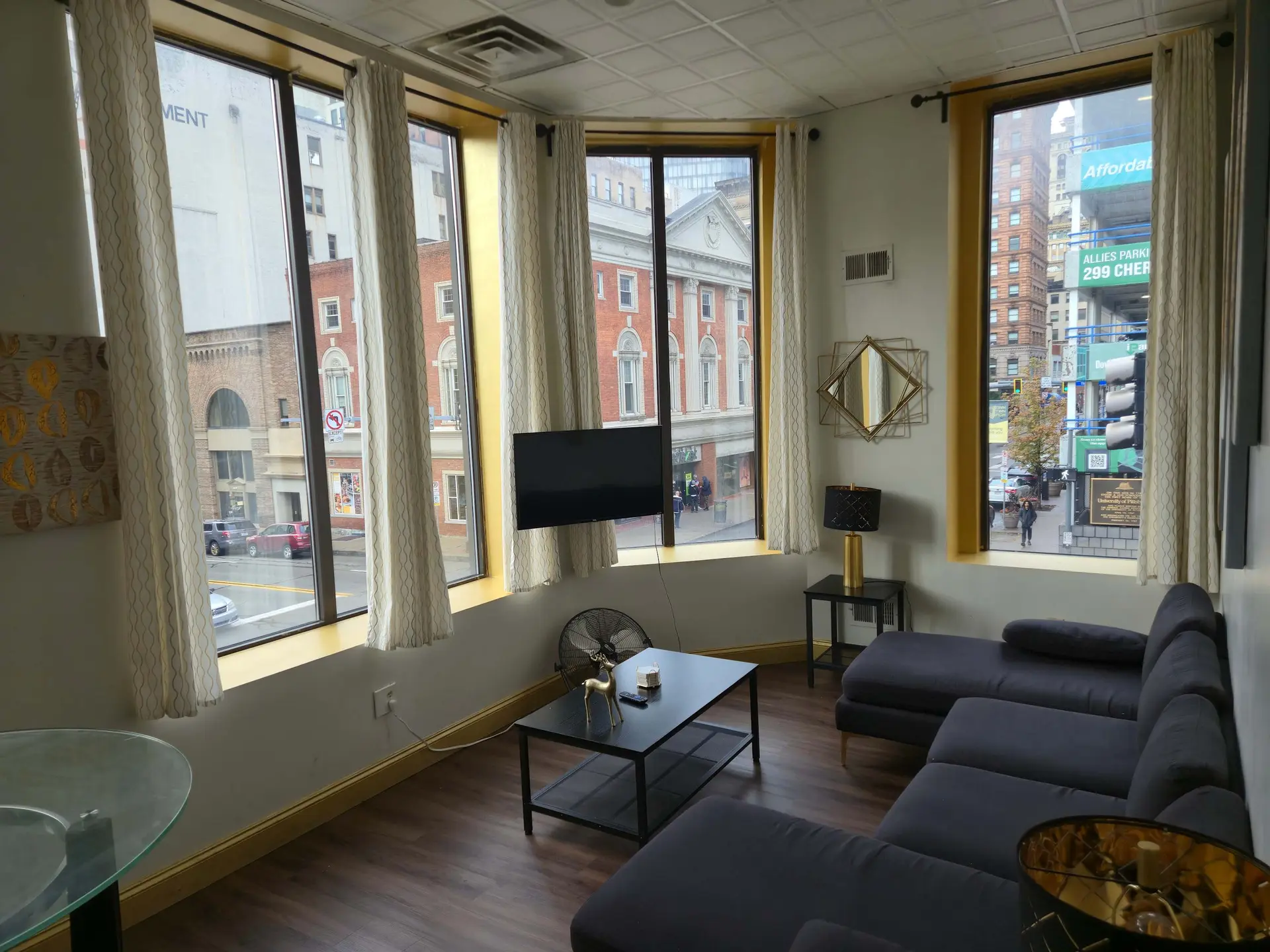 A modern living room with a large window overlooking a city street.