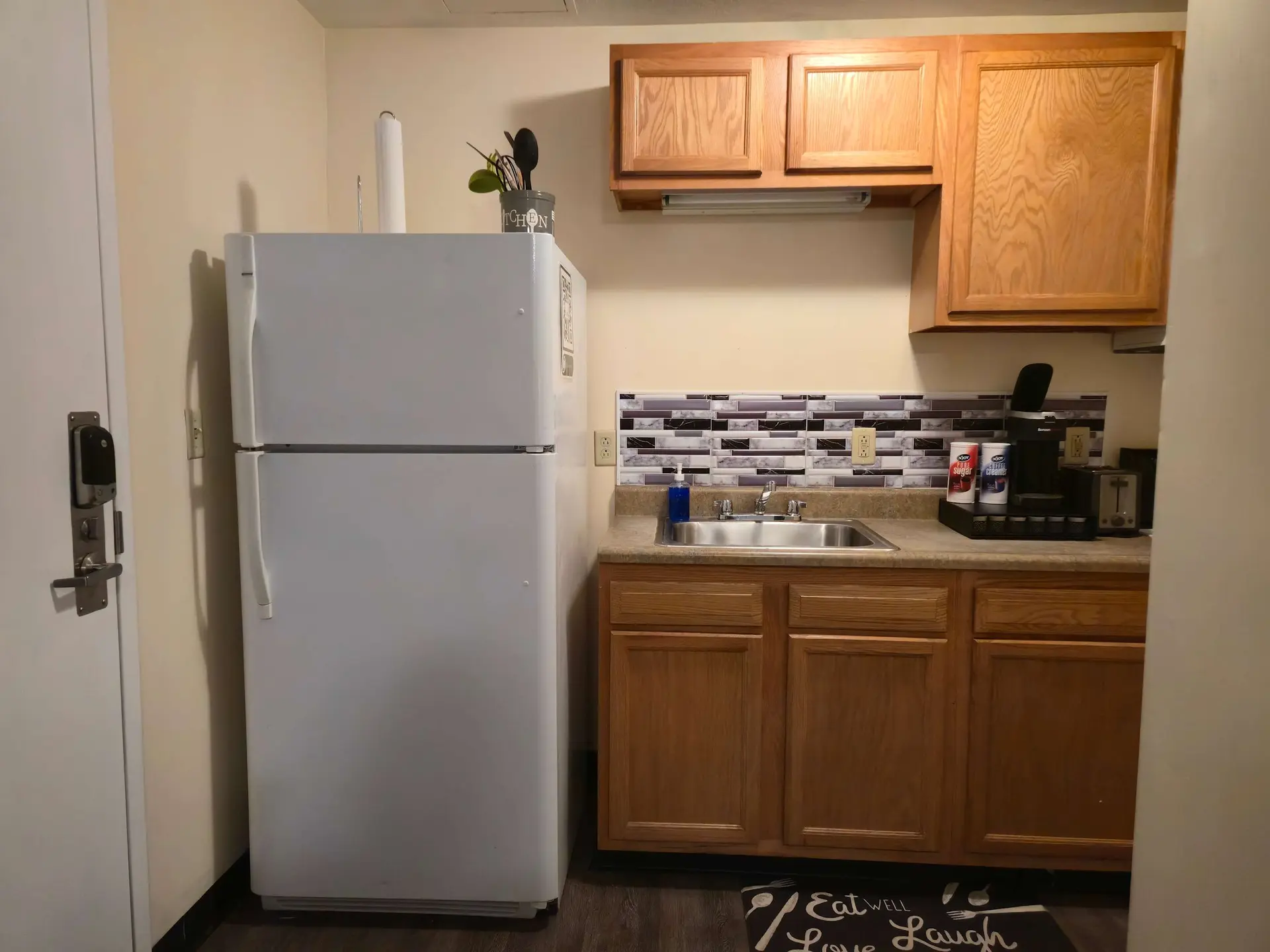 A clean, bright kitchen with a white refrigerator, sink, and cabinets.
