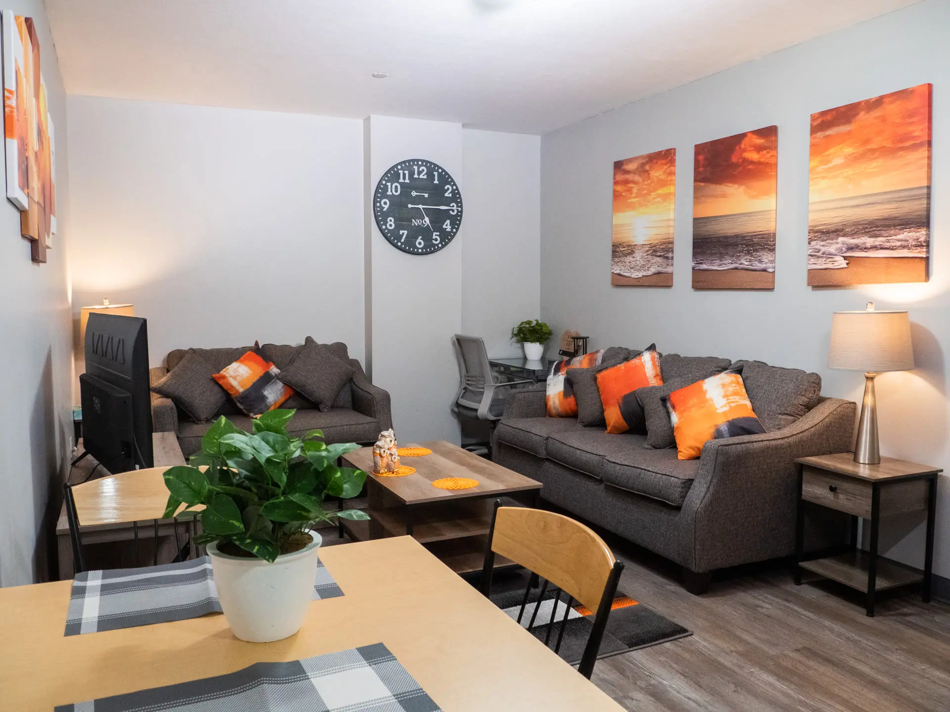 A living room with a dark gray couch, an armchair, and a coffee table with a plant on it.