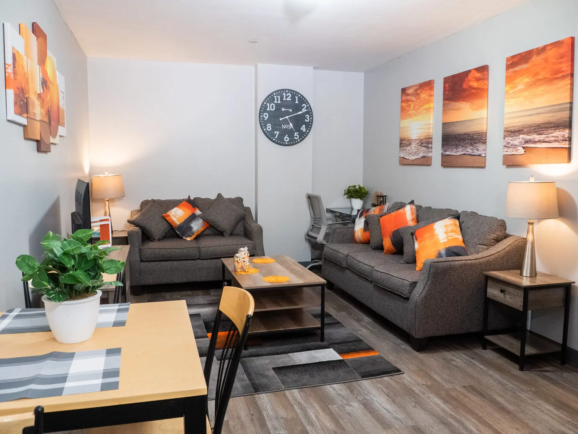 Living room with gray sofas, orange pillows, a coffee table, and a large clock.