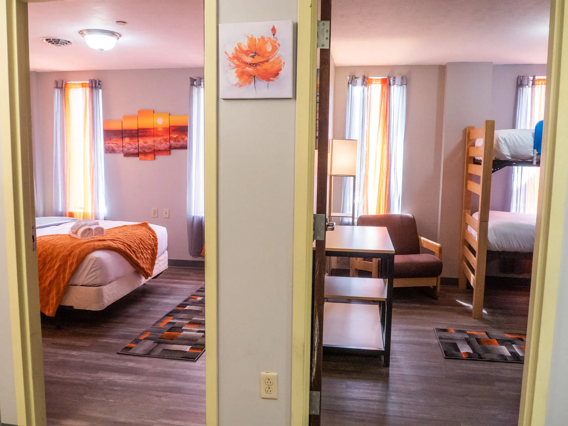 A hallway with two rooms, one with a bed and the other with bunk beds.