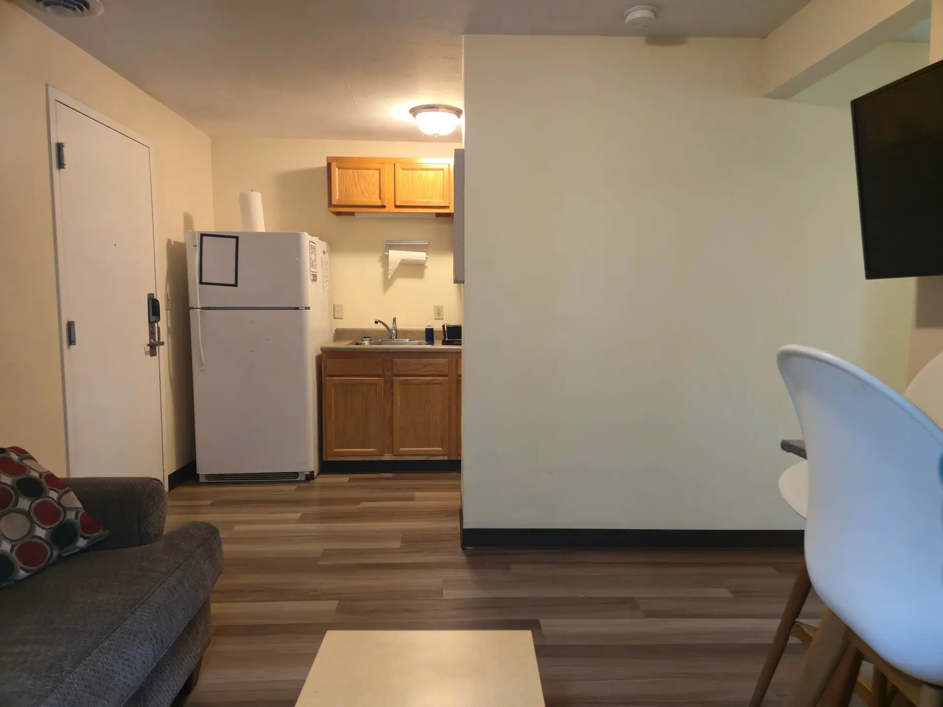 A studio apartment with a kitchenette, a refrigerator, a sofa, and a TV.