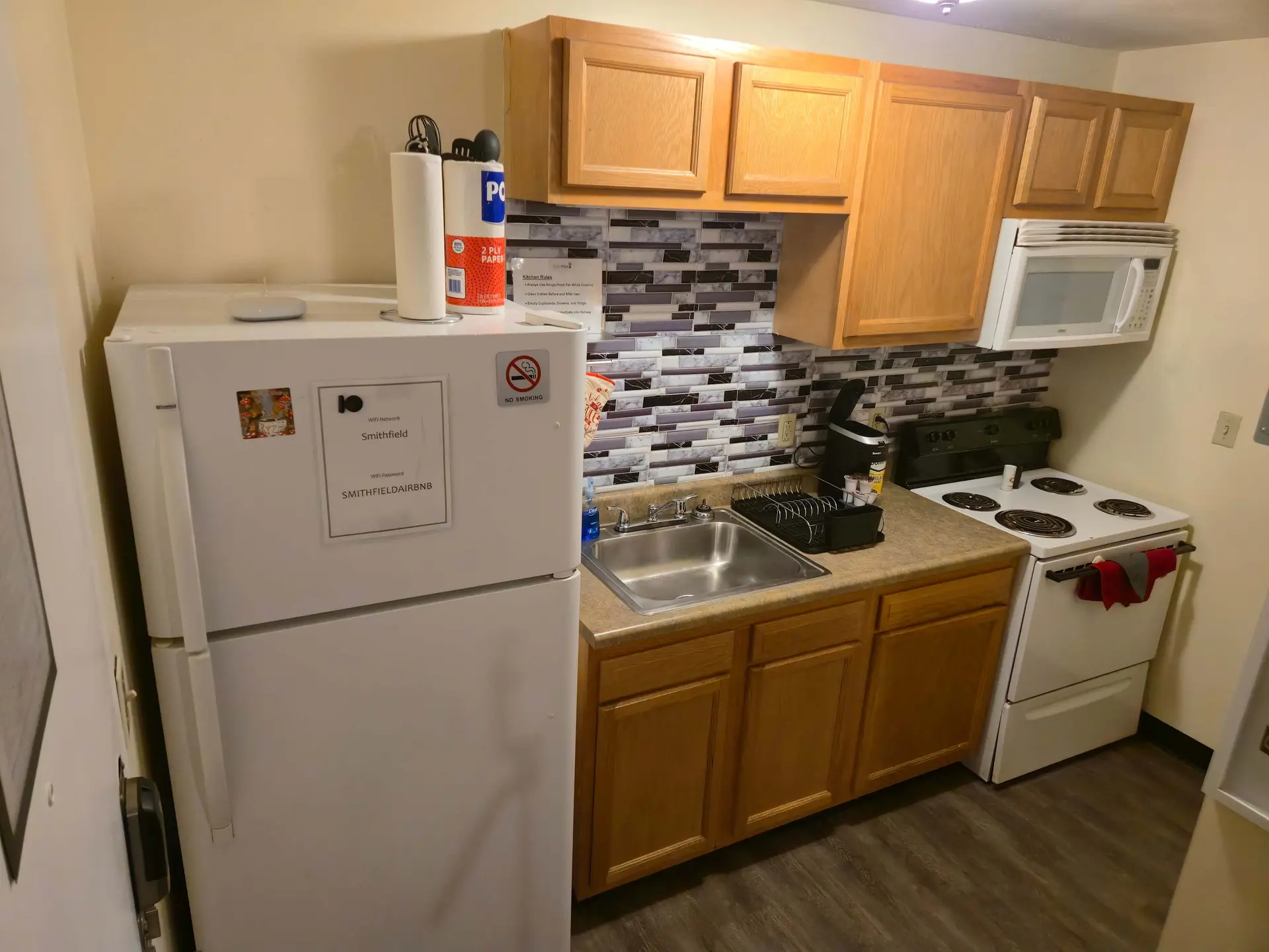 Kitchen with white refrigerator, microwave, stove, sink, and cabinets.