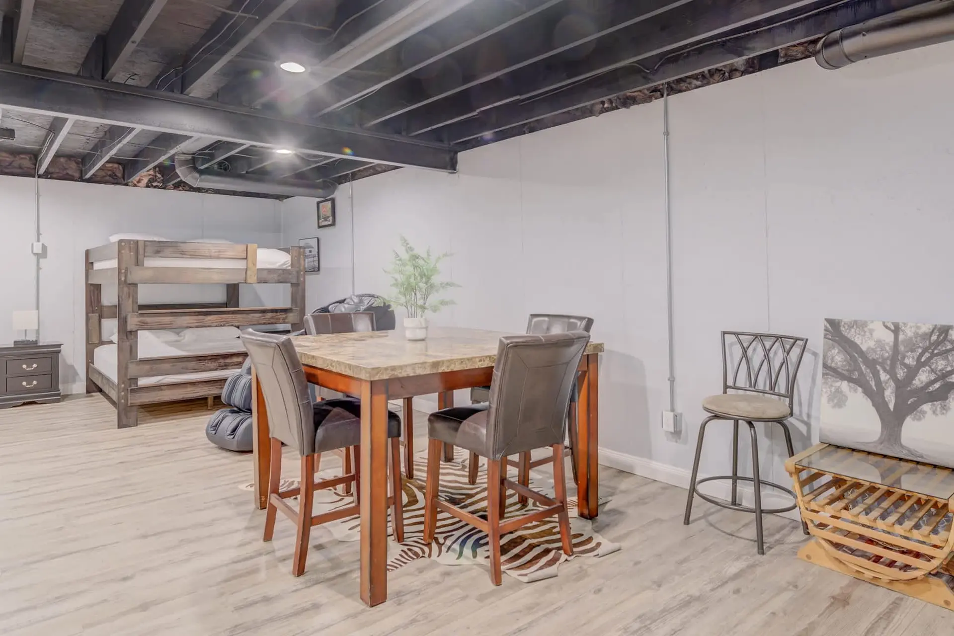 A basement room with a dining set, bunk beds, and decor.