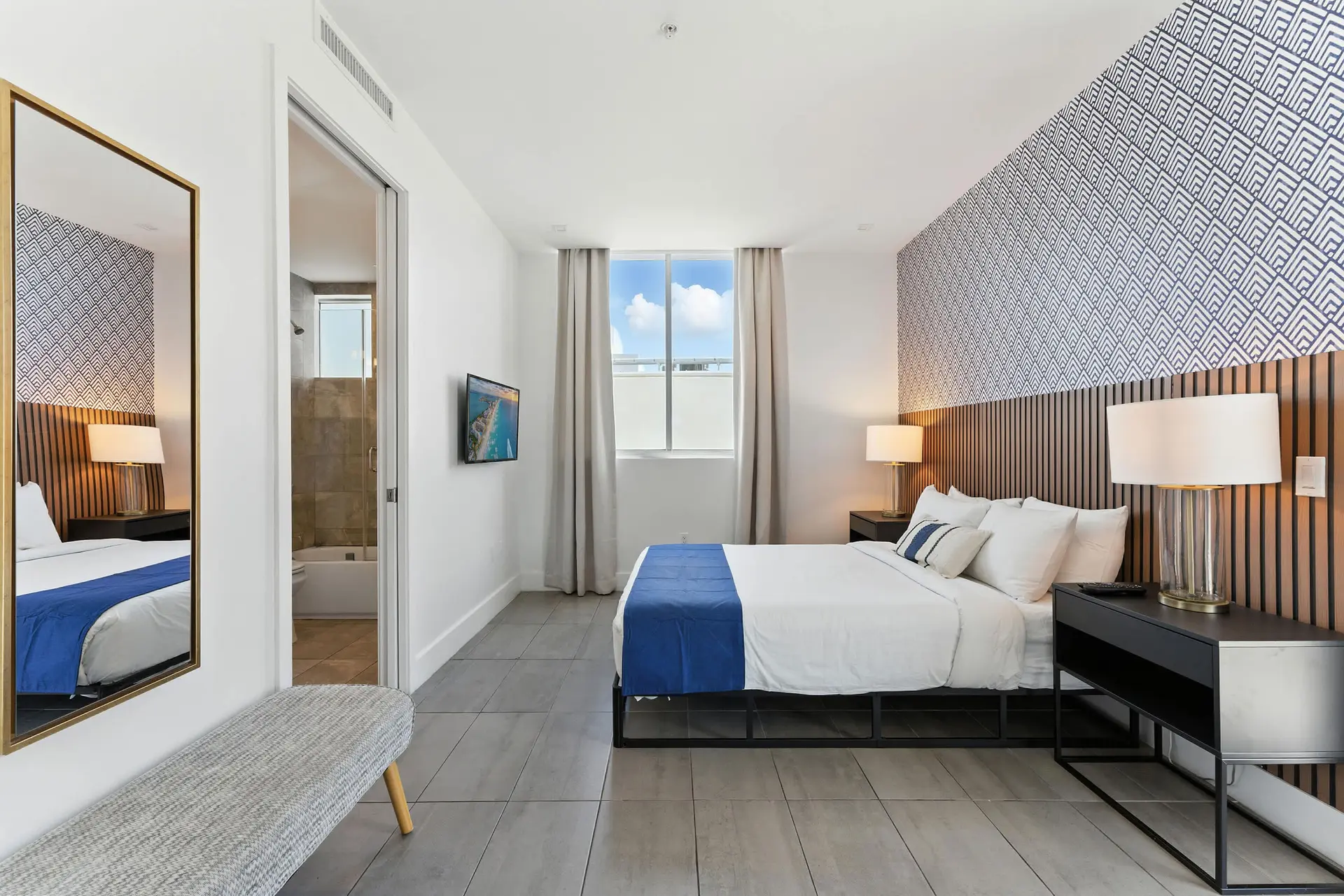A modern bedroom with a king-sized bed, blue accents, and patterned wallpaper.