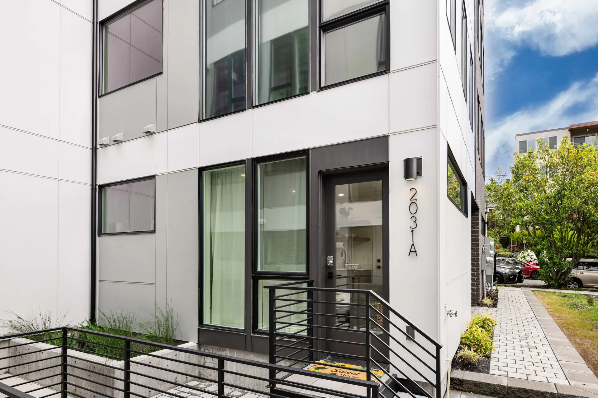 Modern townhouse exterior with large windows, a black front door, and house numbers.