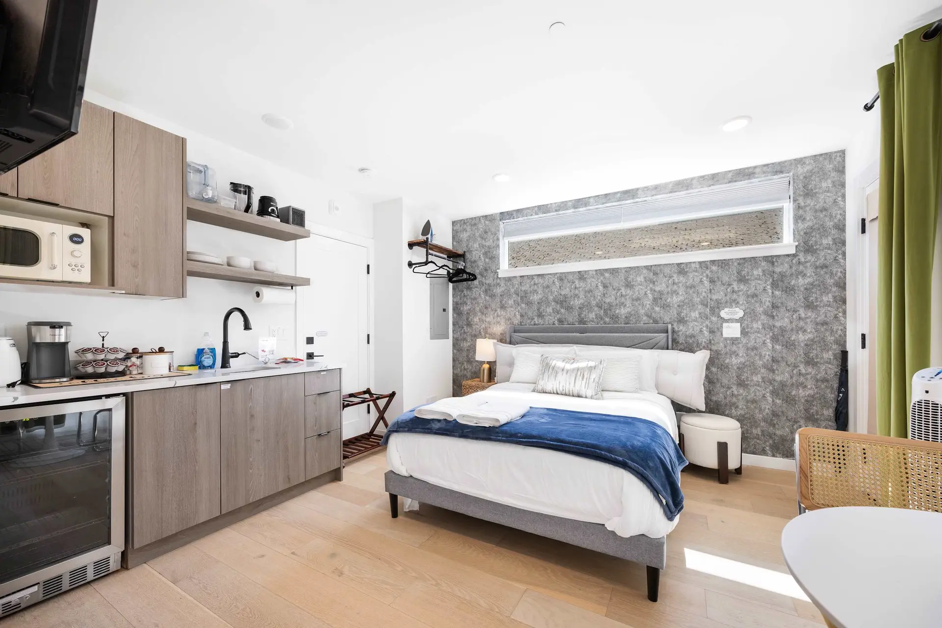 A bed and kitchenette in a studio apartment with a minimalist design.