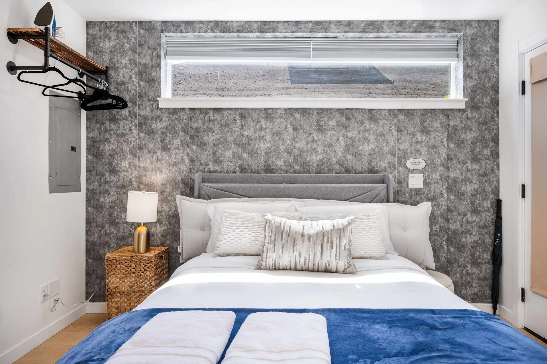 A neatly made bed with white sheets, a blue blanket, and two white towels.