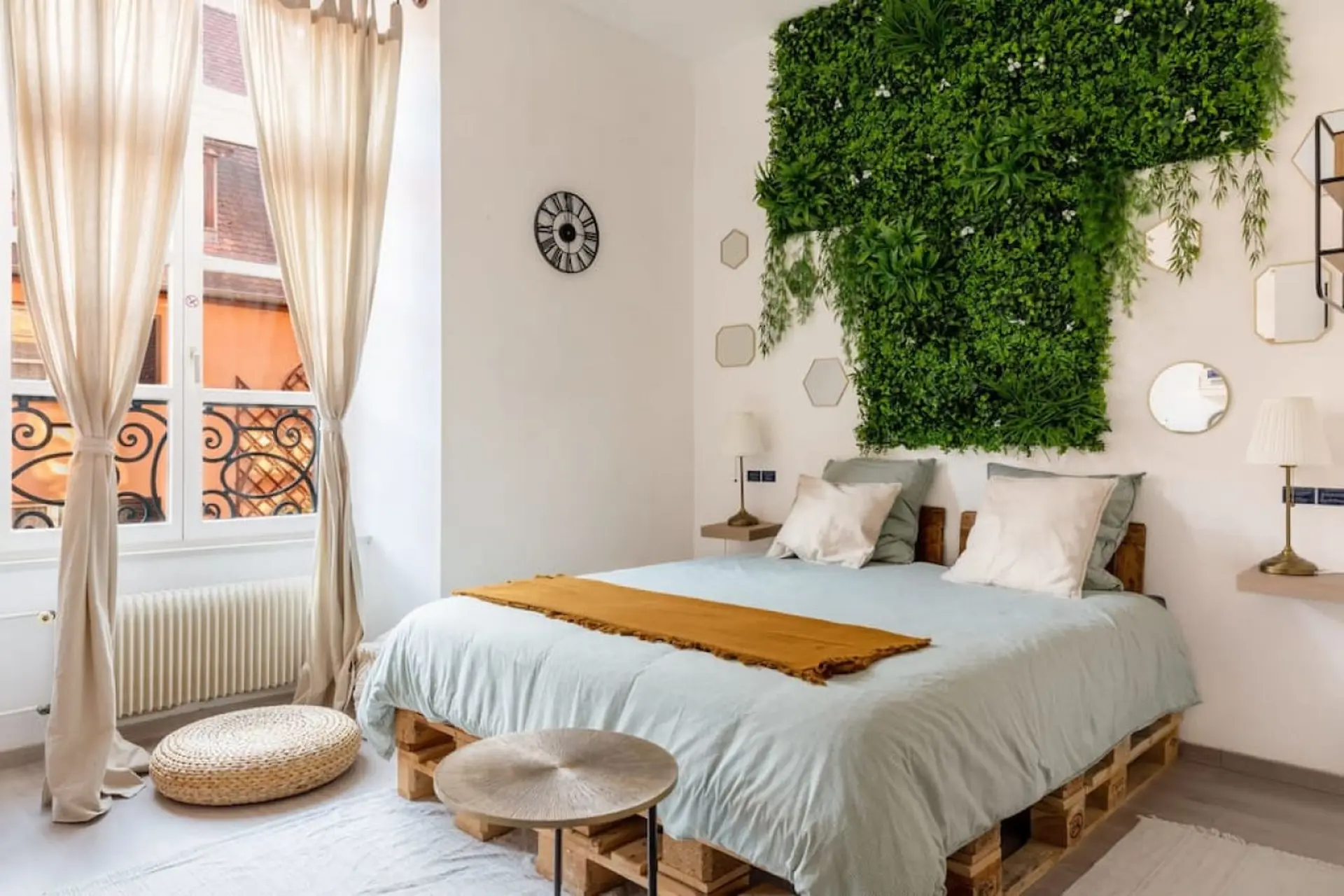Bedroom with a bed made of pallets and a green wall decor.