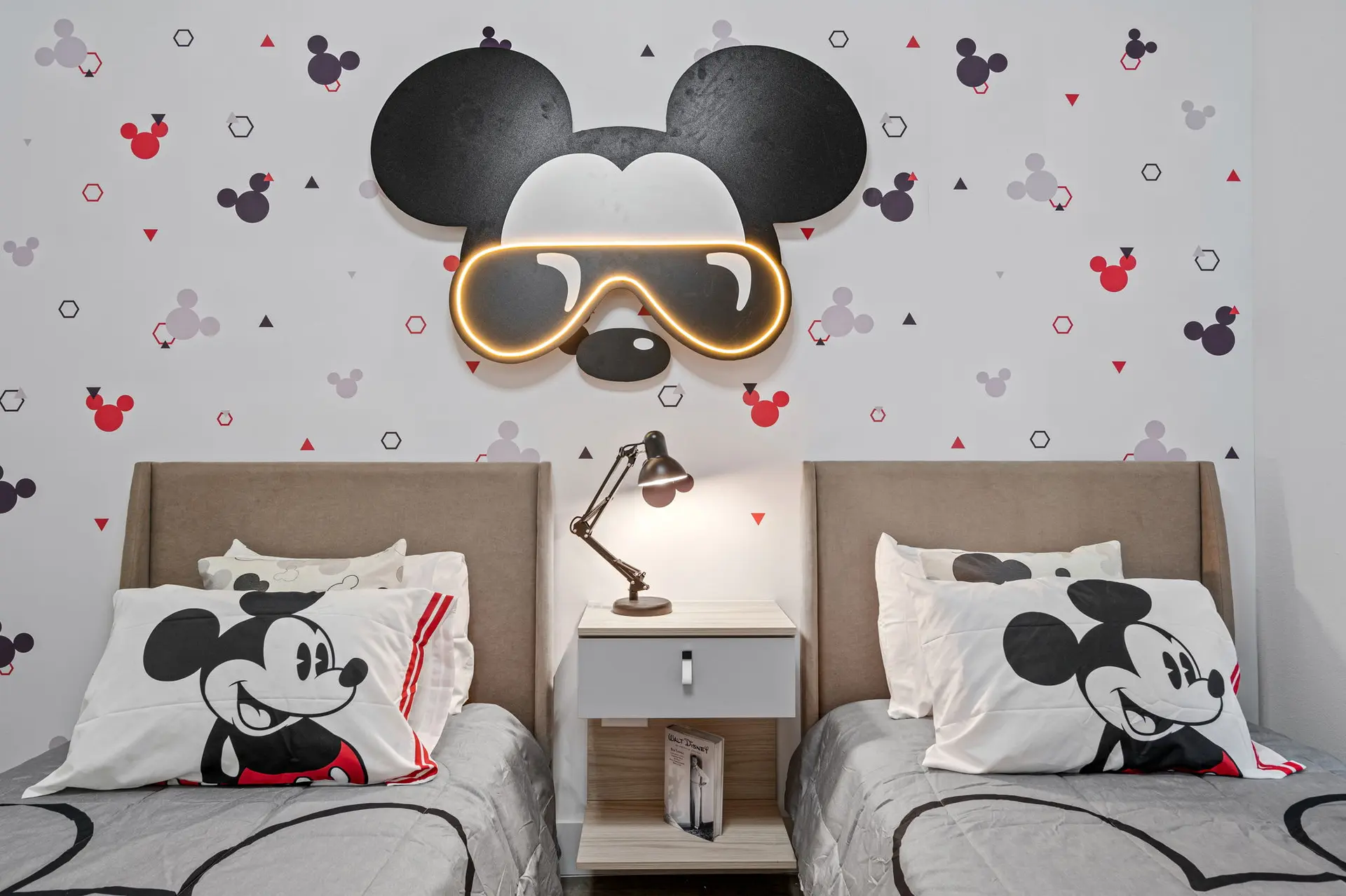 Two beds with Mickey Mouse-themed pillows and bedding.