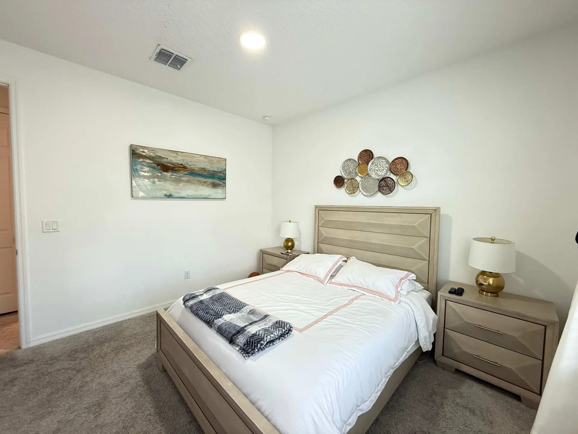 A bedroom with a bed, nightstands, and wall decor.