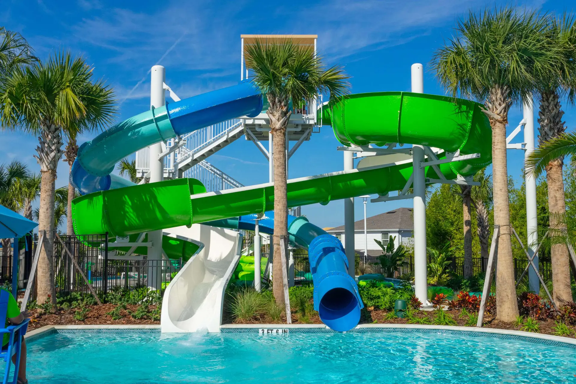 Water slides, palm trees, and a pool on a sunny day.