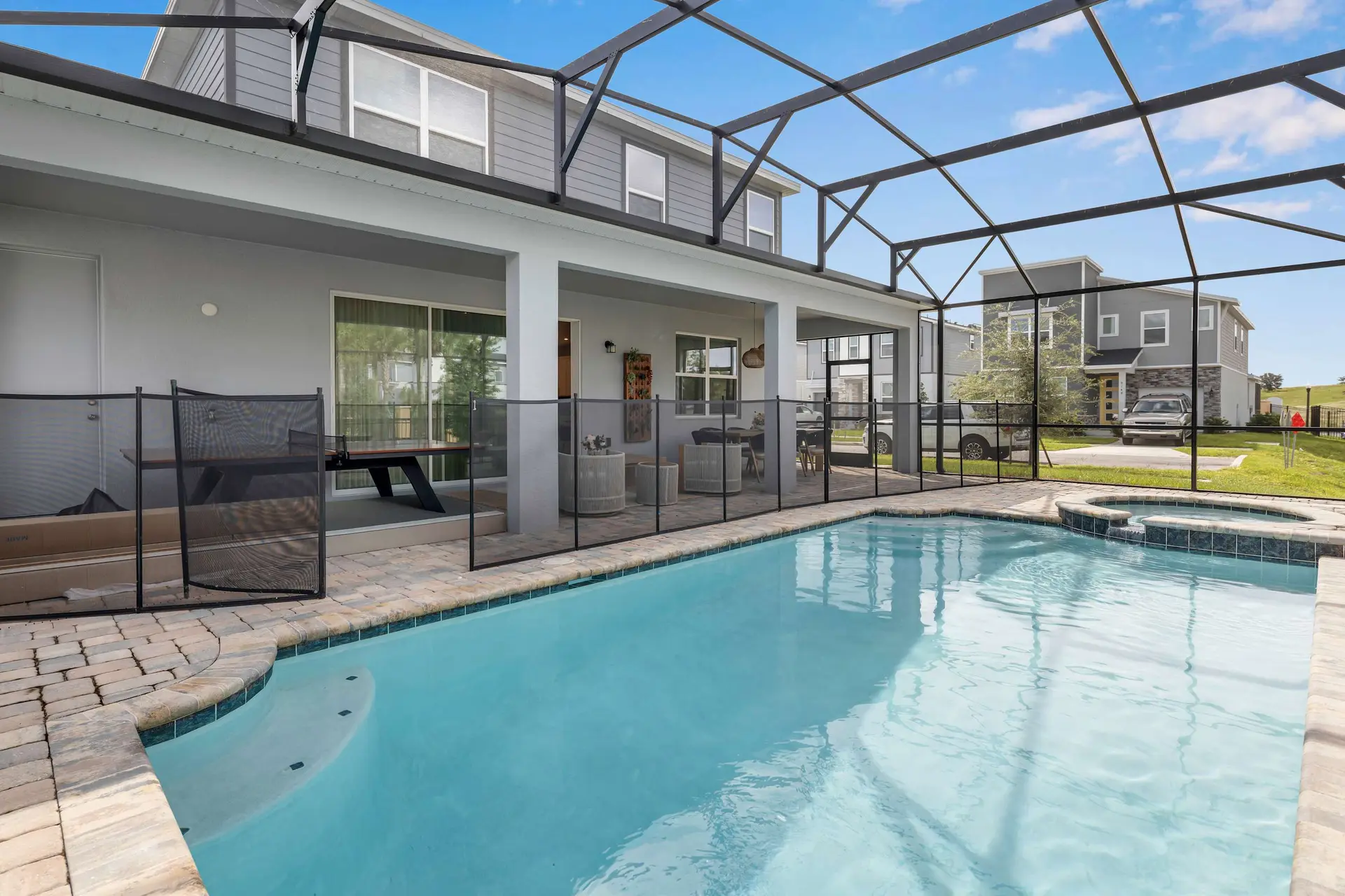A backyard pool with a spa, screened enclosure, and outdoor living space.
