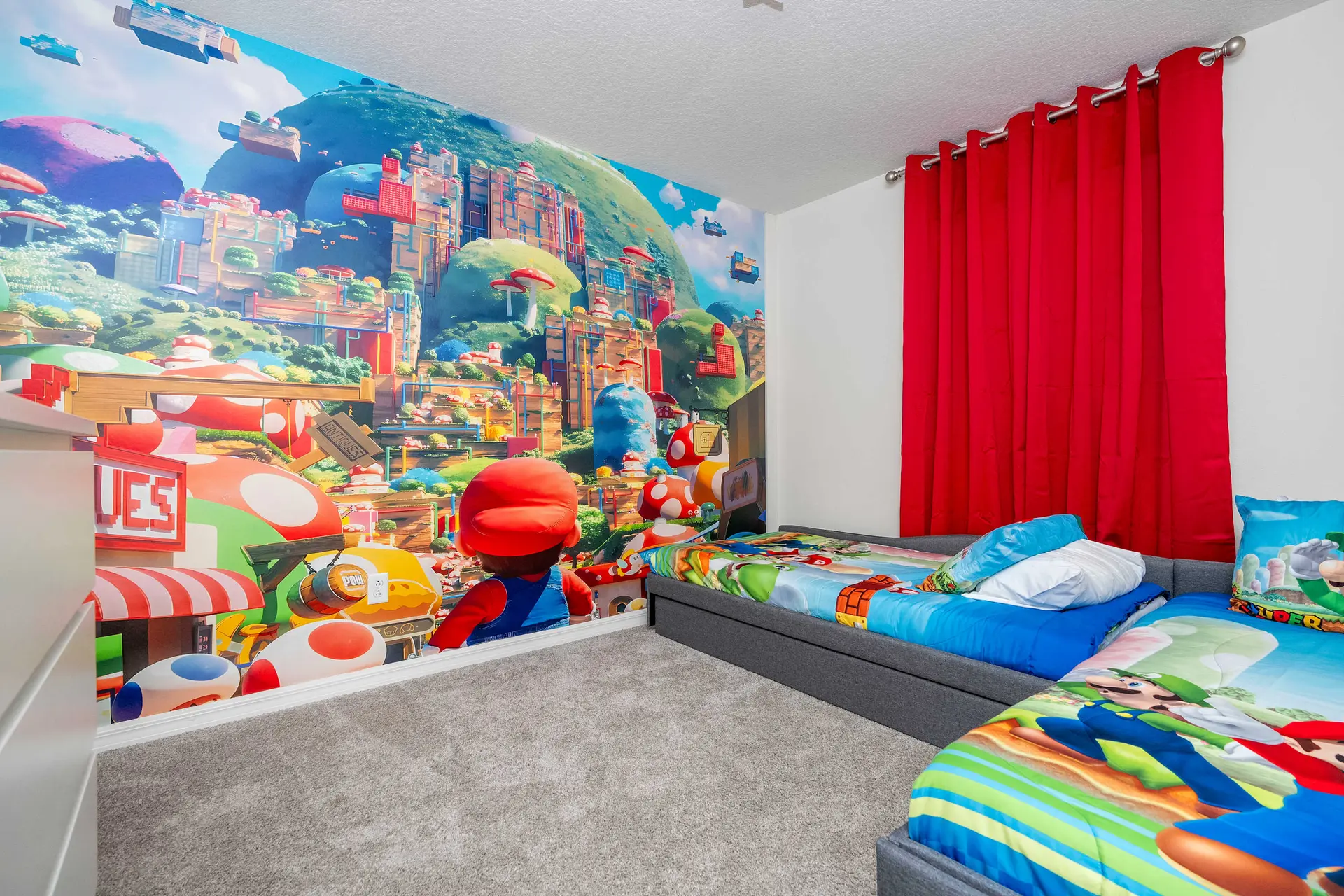 A kid's bedroom with a vibrant Mario-themed mural and two twin beds.