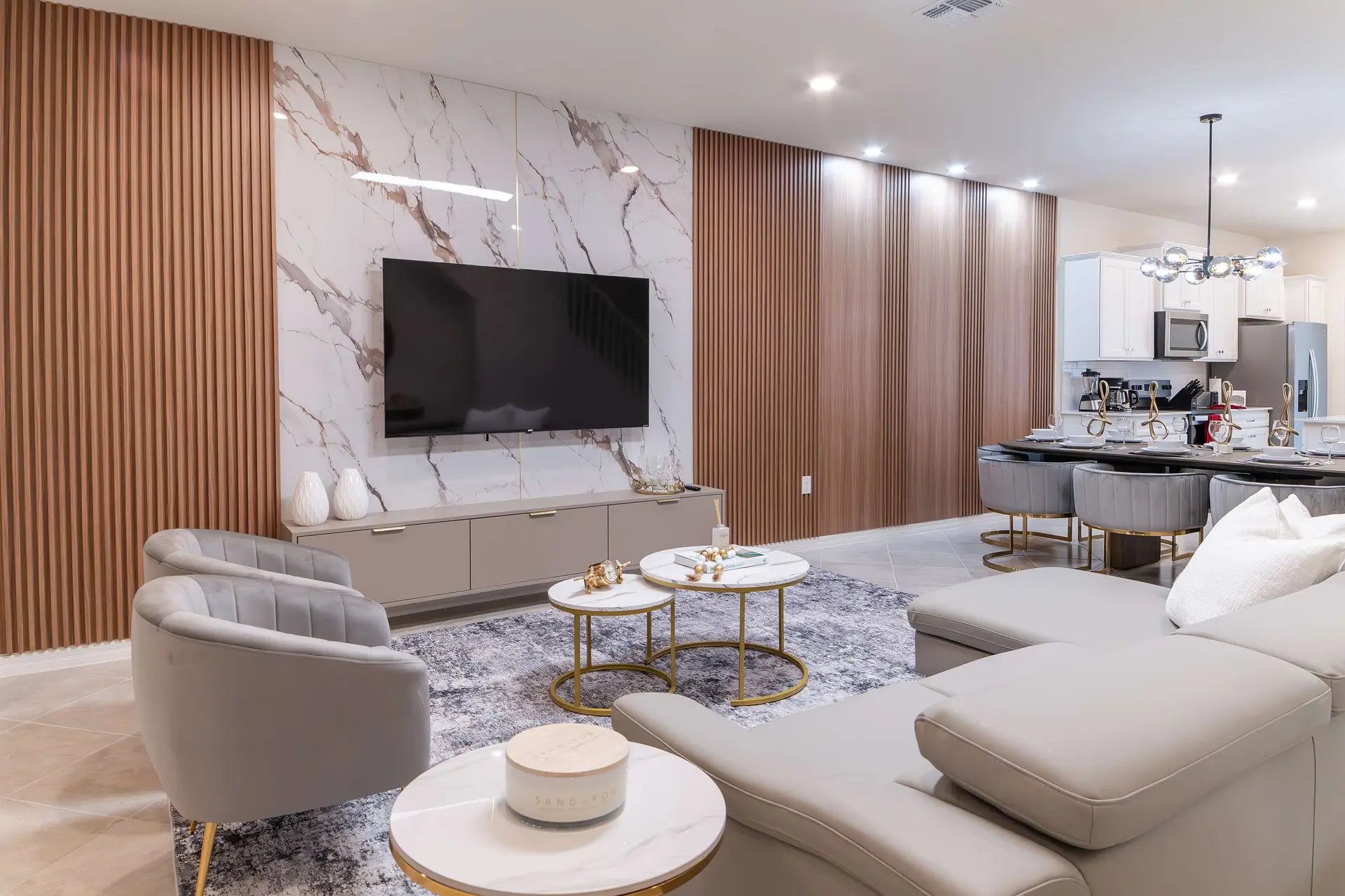 A modern living room with a gray sectional sofa, marble accents, and wood slat walls.