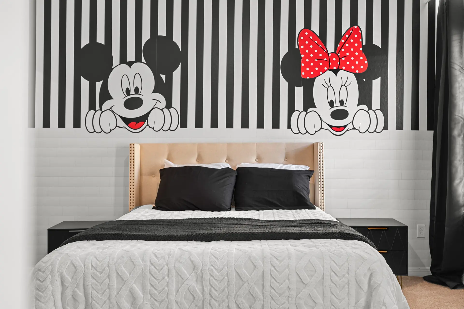 Mickey and Minnie Mouse themed bedroom with a tufted headboard and black and white striped wallpaper